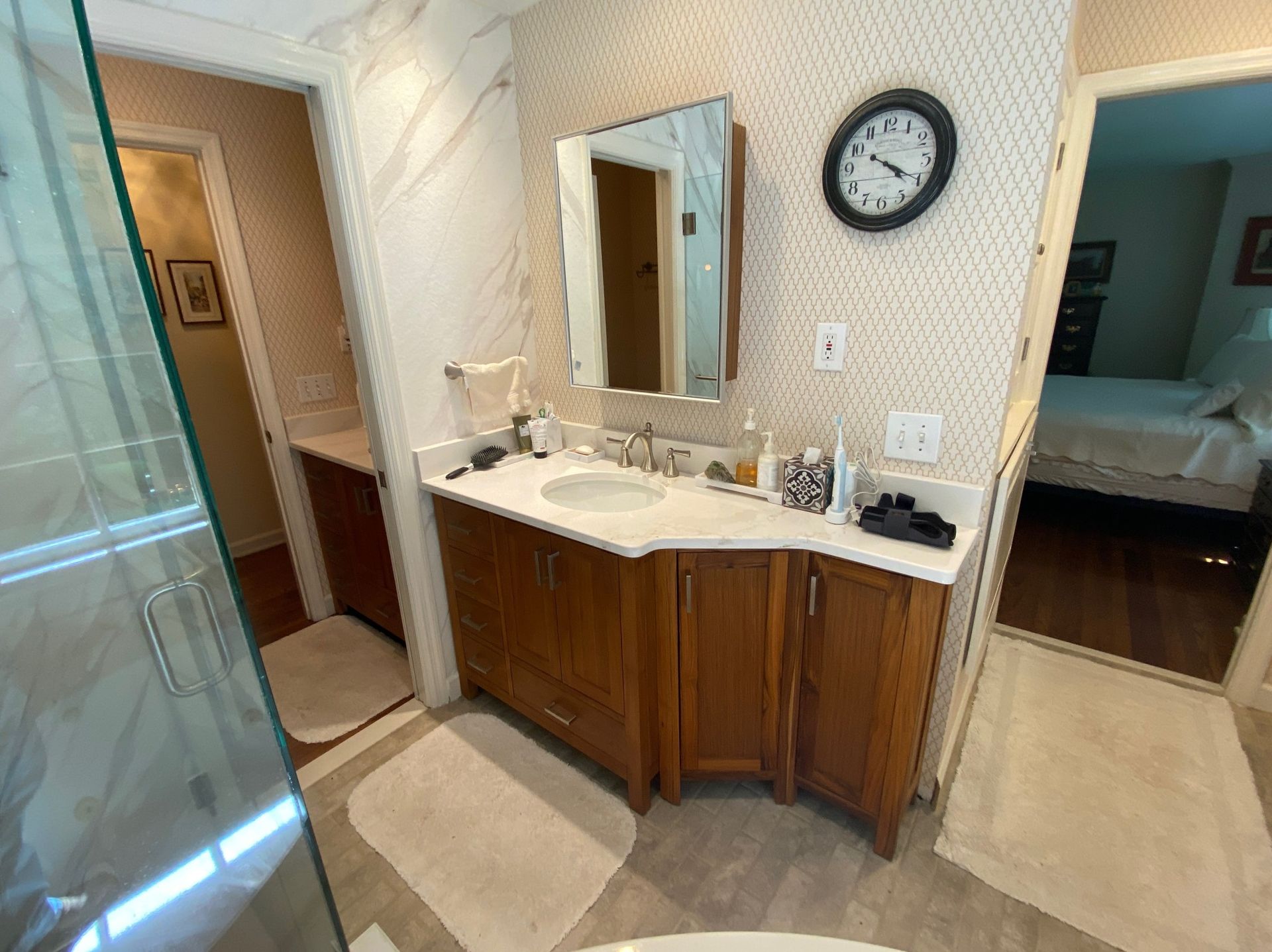 A bathroom with two sinks , a mirror and a clock on the wall.