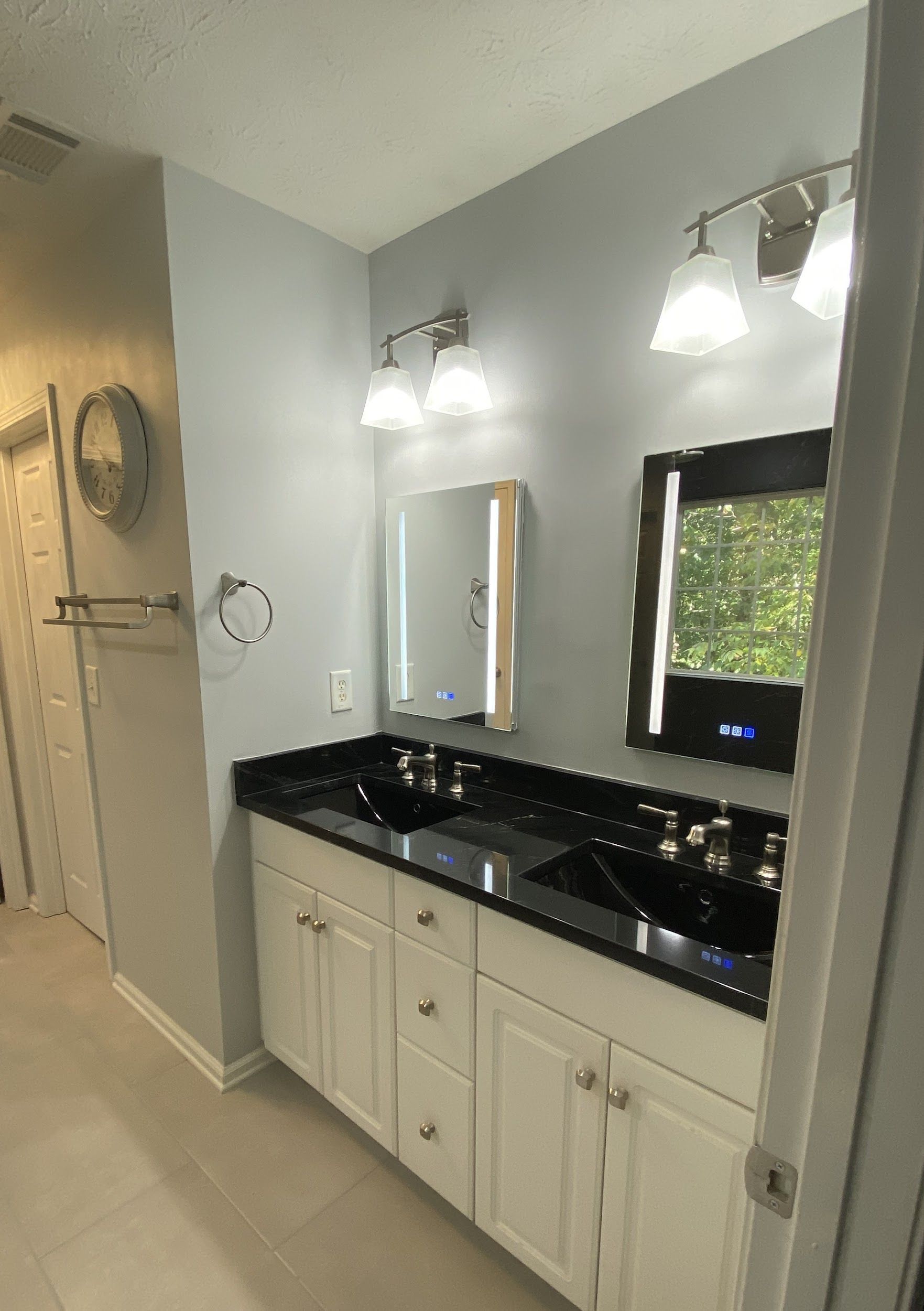 A bathroom with two sinks , a mirror and a window.