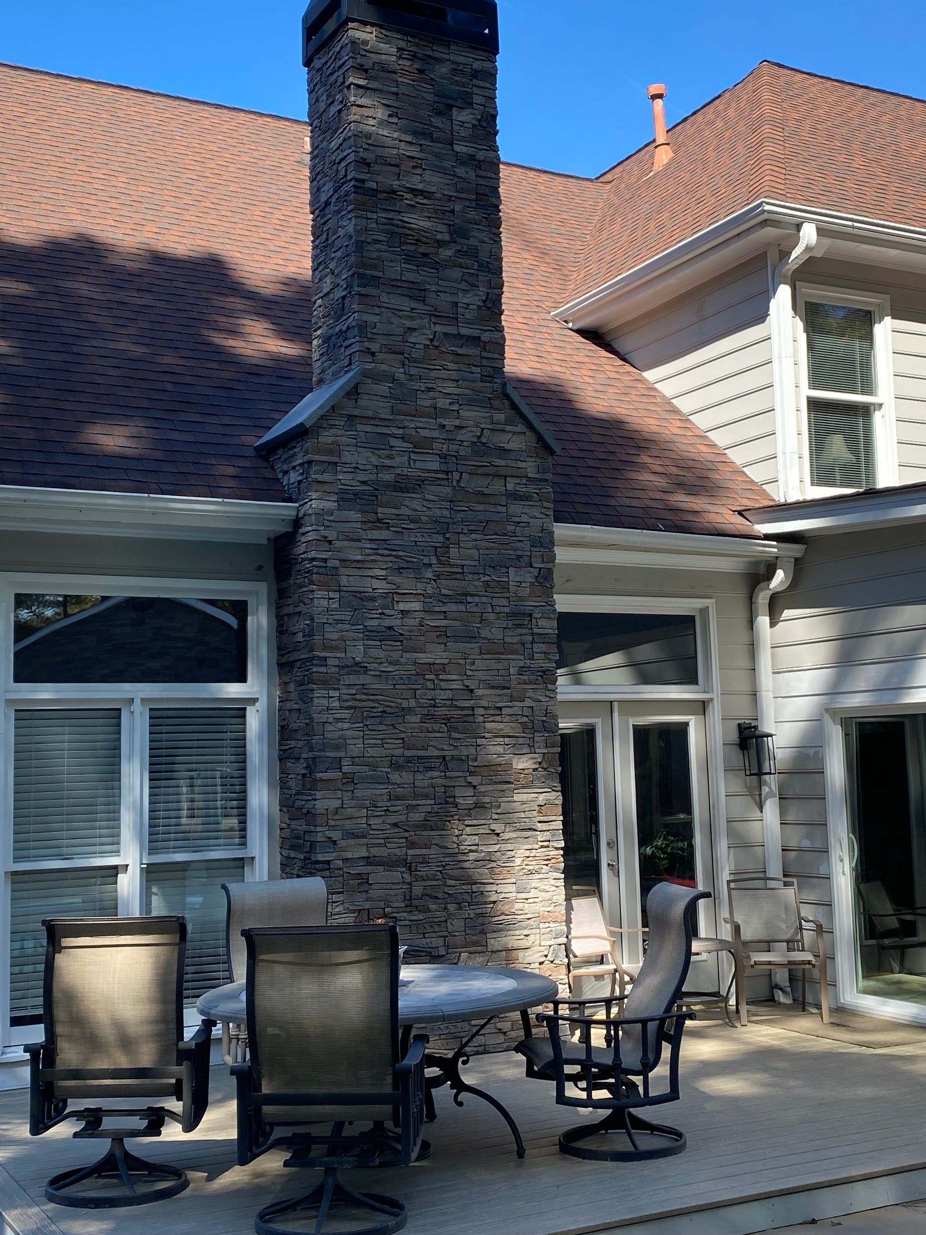 There is a large stone chimney on the side of the house.