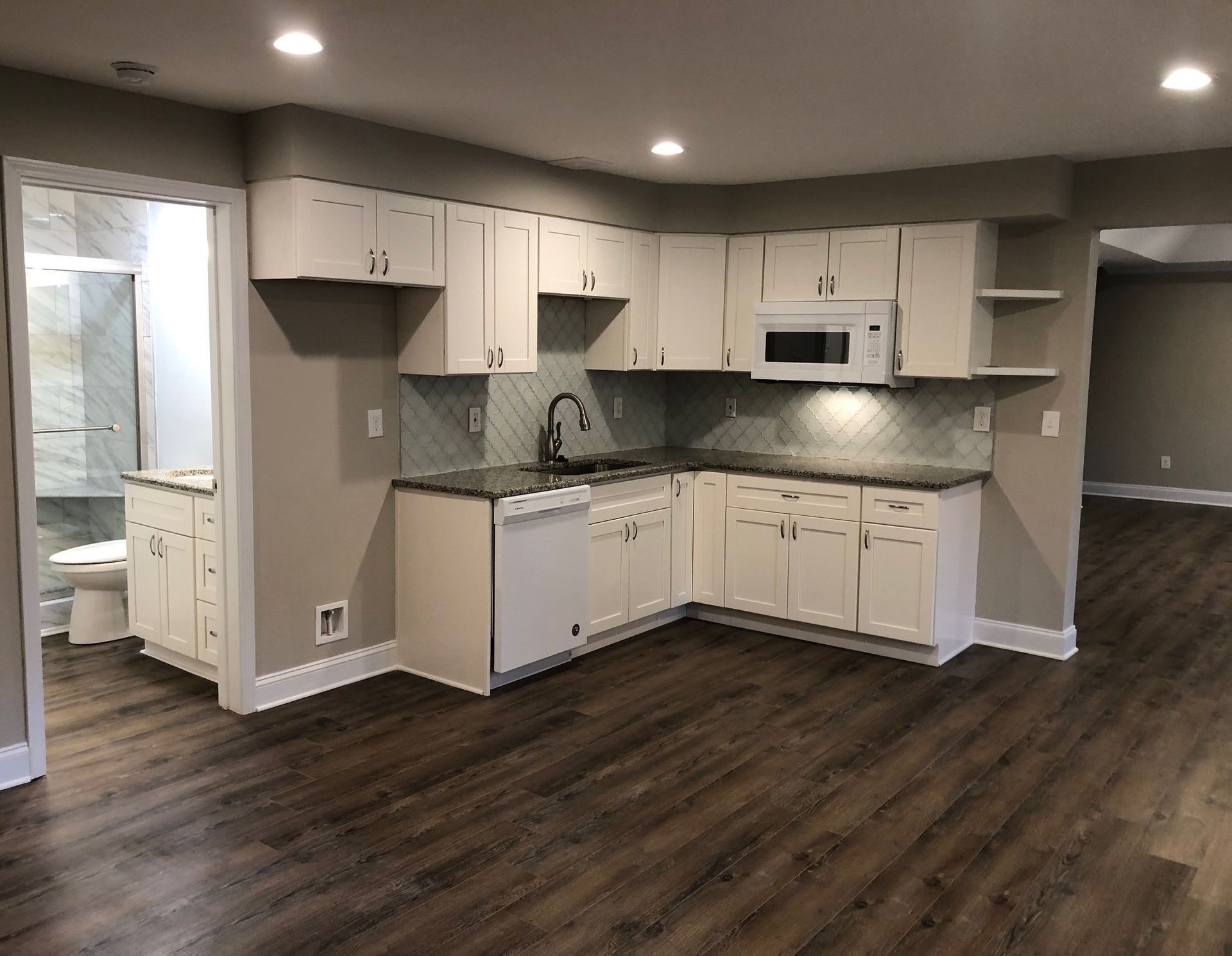 A wooden deck with a screened in porch and a brick house in the background