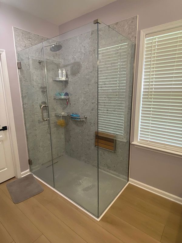 A bathroom with a walk in shower and a window.