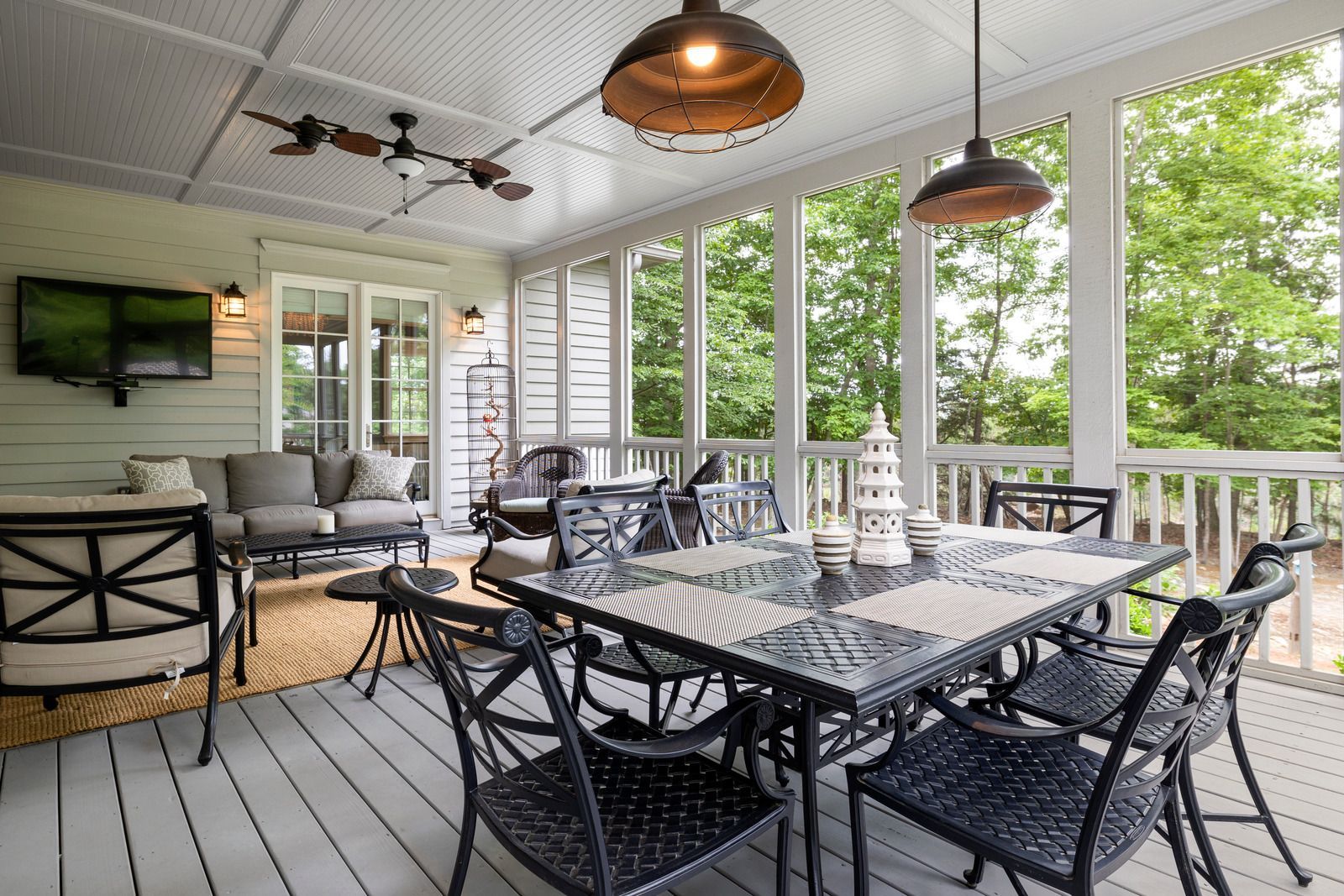 A screened in porch with a table and chairs and a television.