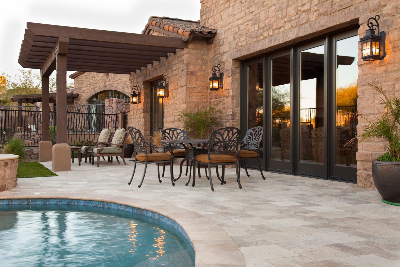 A patio with a table and chairs next to a pool.