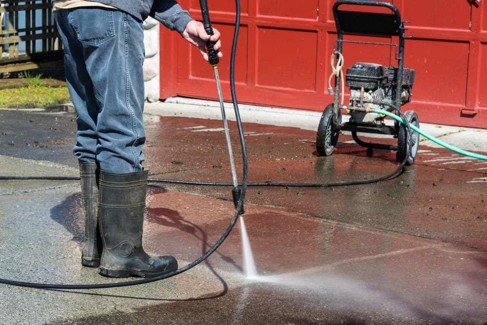 a man is using a high pressure washer to clean a driveway