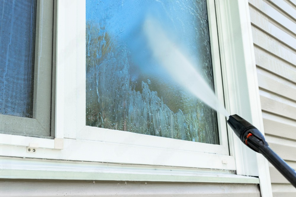 a person is cleaning a window with a high pressure washer