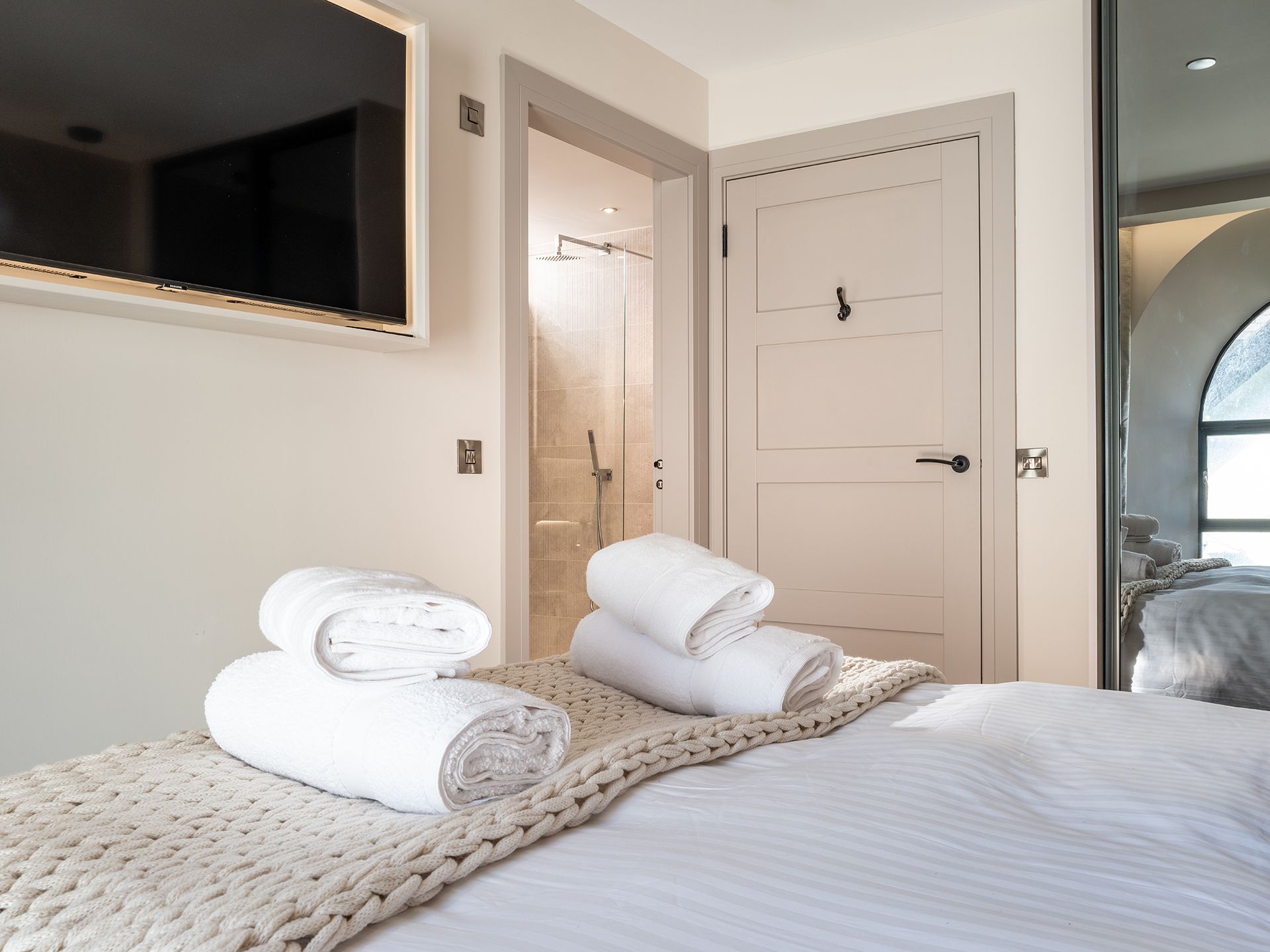 A bedroom with a bed and a television on the wall