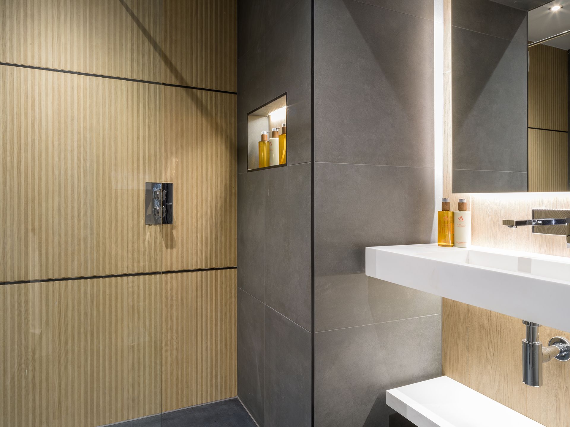 A bathroom with a sink , mirror and shower.