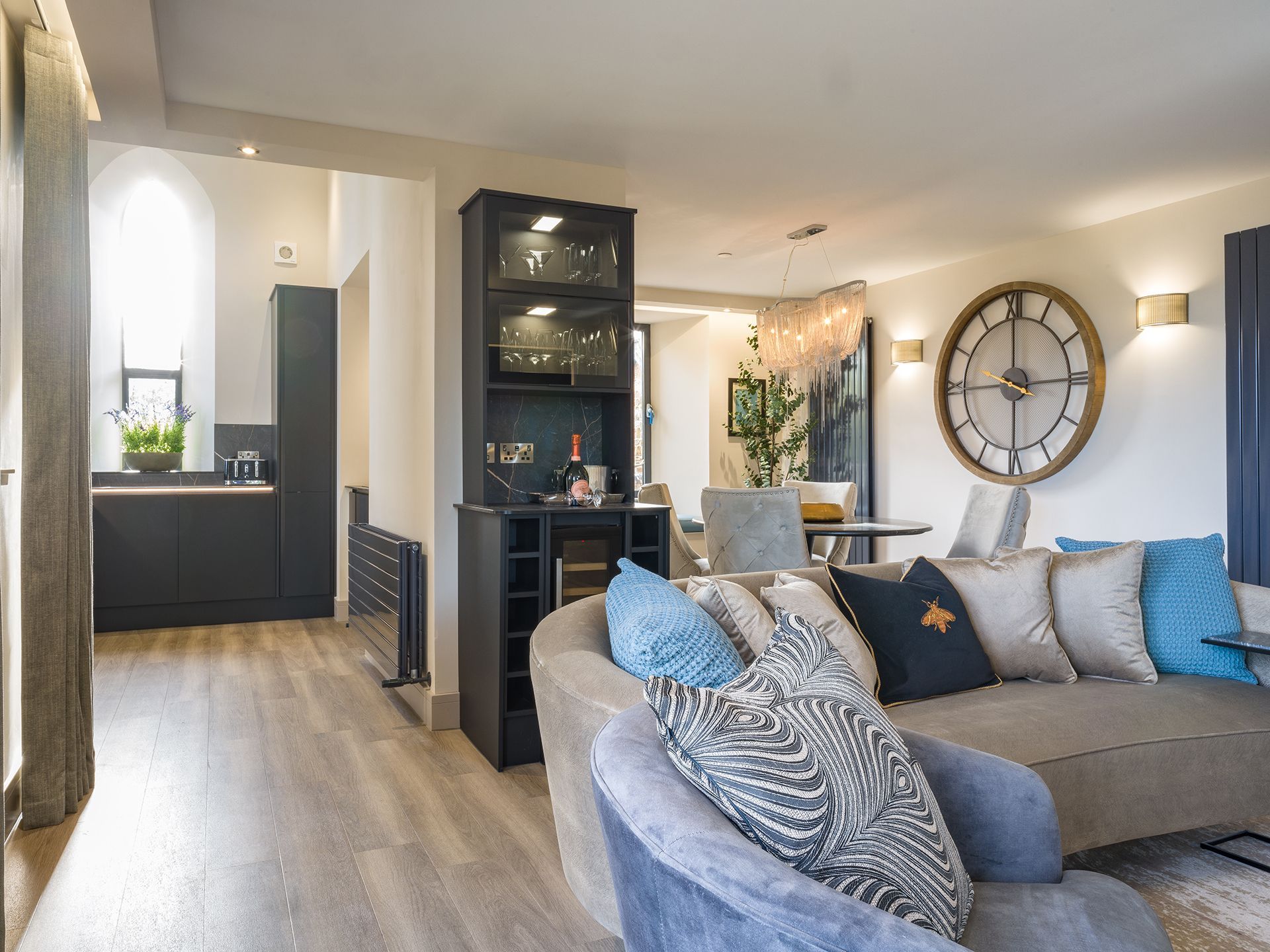 A living room with a couch , chair , and clock on the wall.