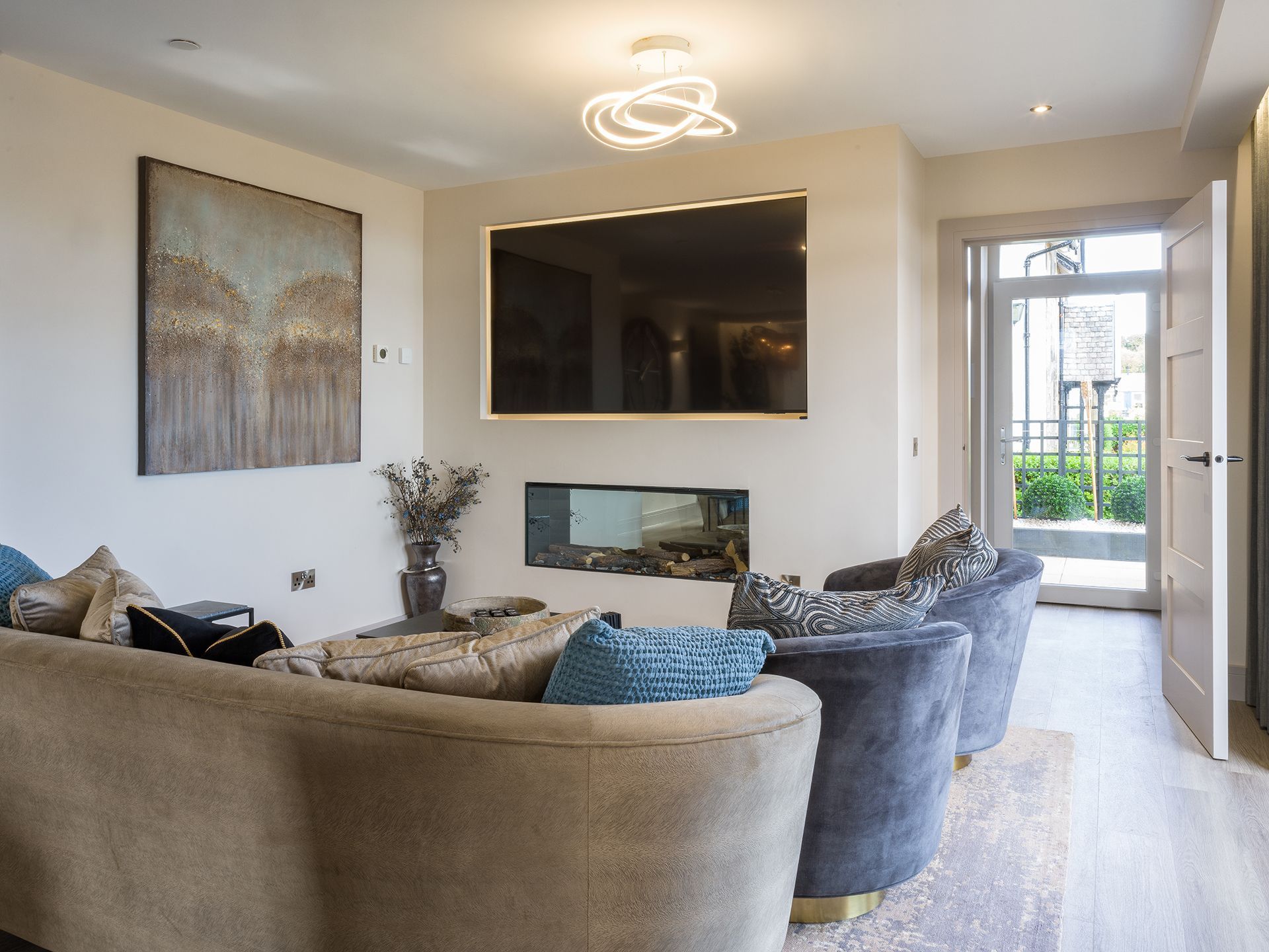 A living room with a couch , chairs , television and fireplace.