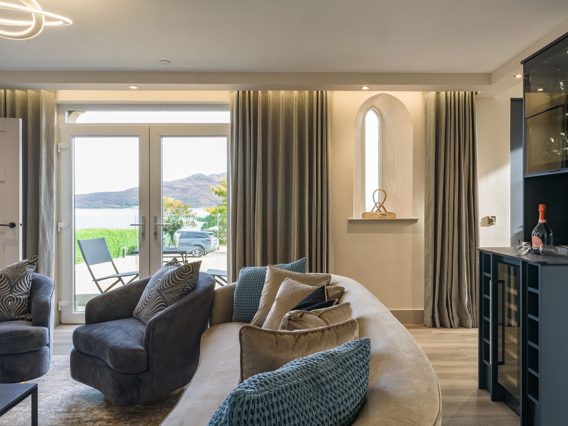 A living room with a couch , chairs , and a wine cooler.