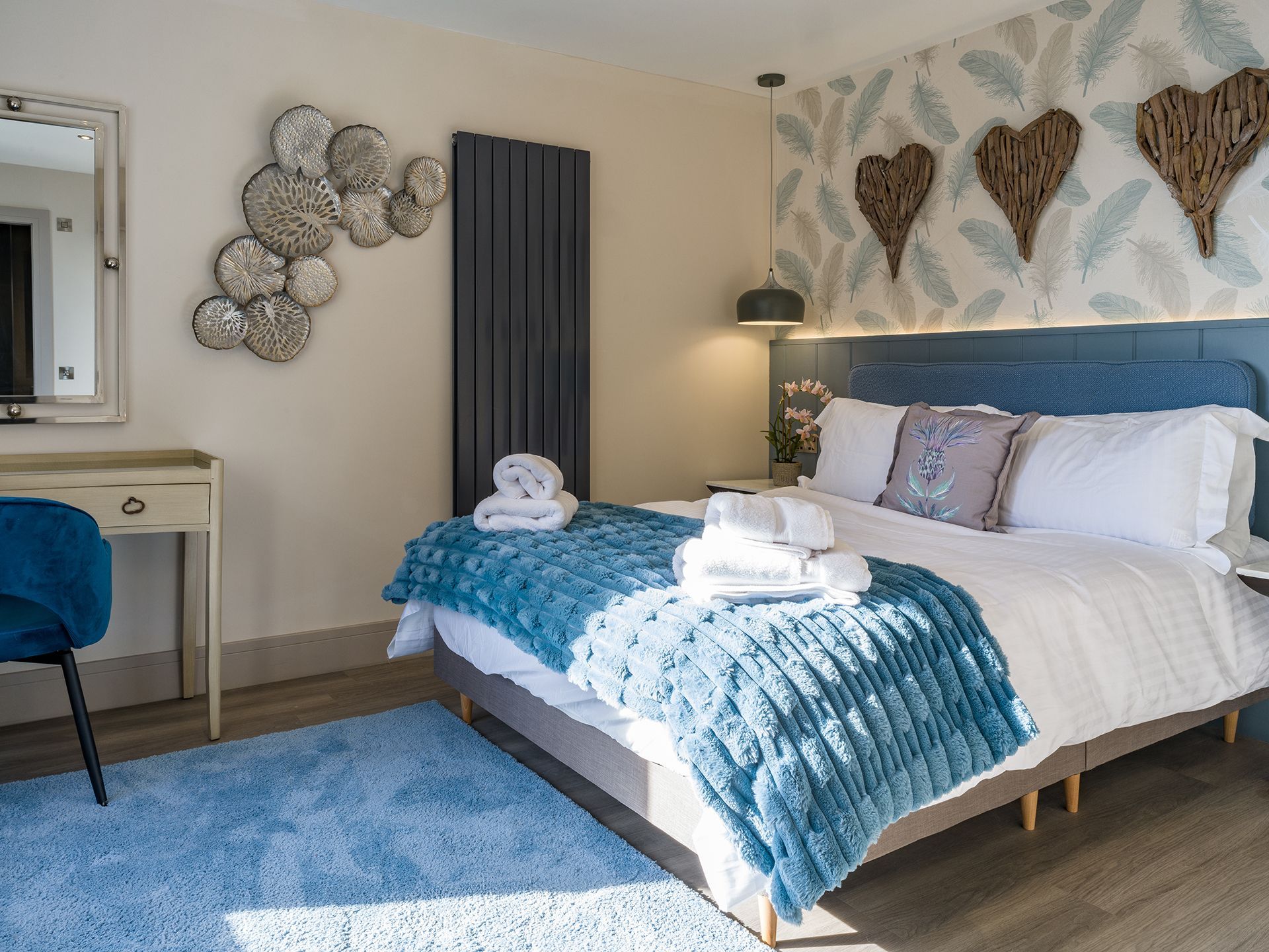 A bedroom with a large bed , a desk , and a mirror.