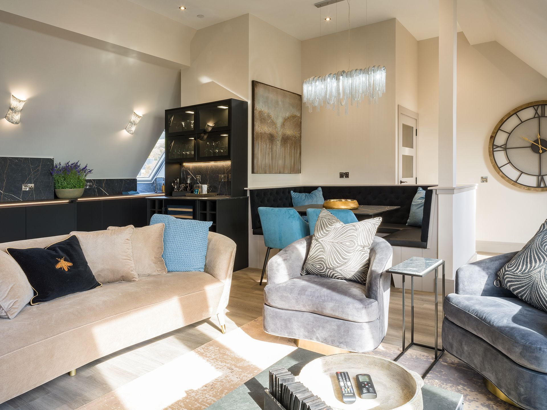 A living room with a couch , chair , table and a clock on the wall.