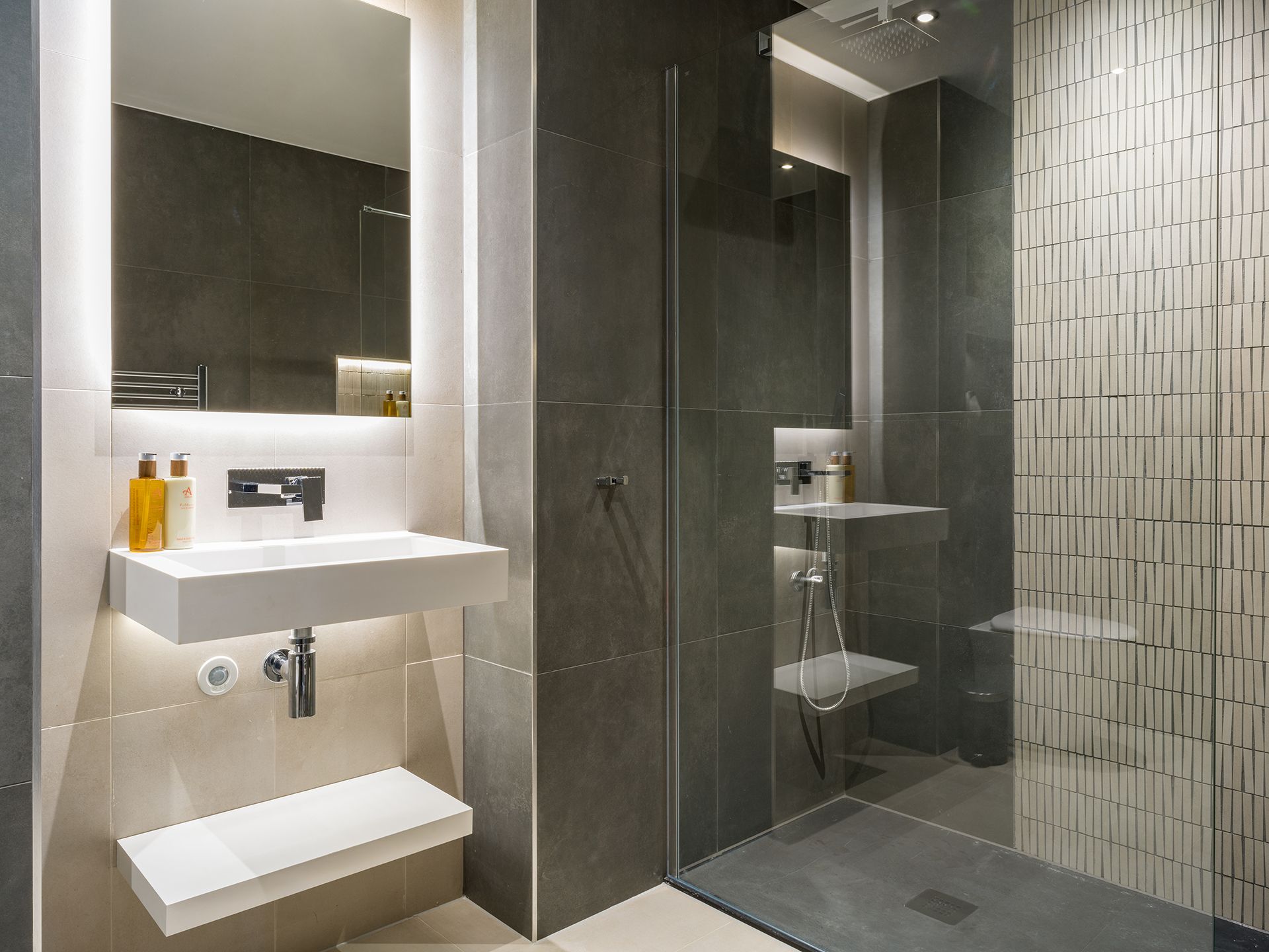 A bathroom with a sink , mirror and walk in shower.
