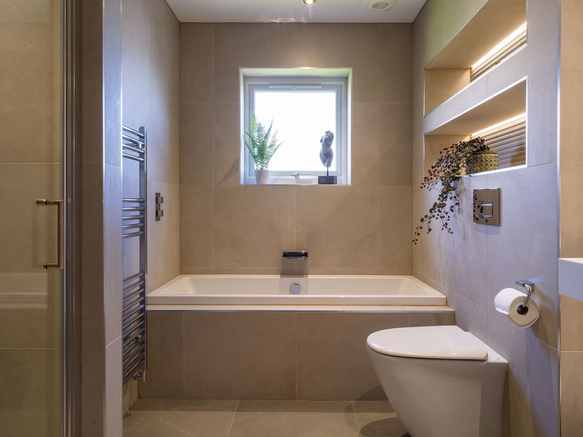 A bathroom with a tub , toilet , and window.