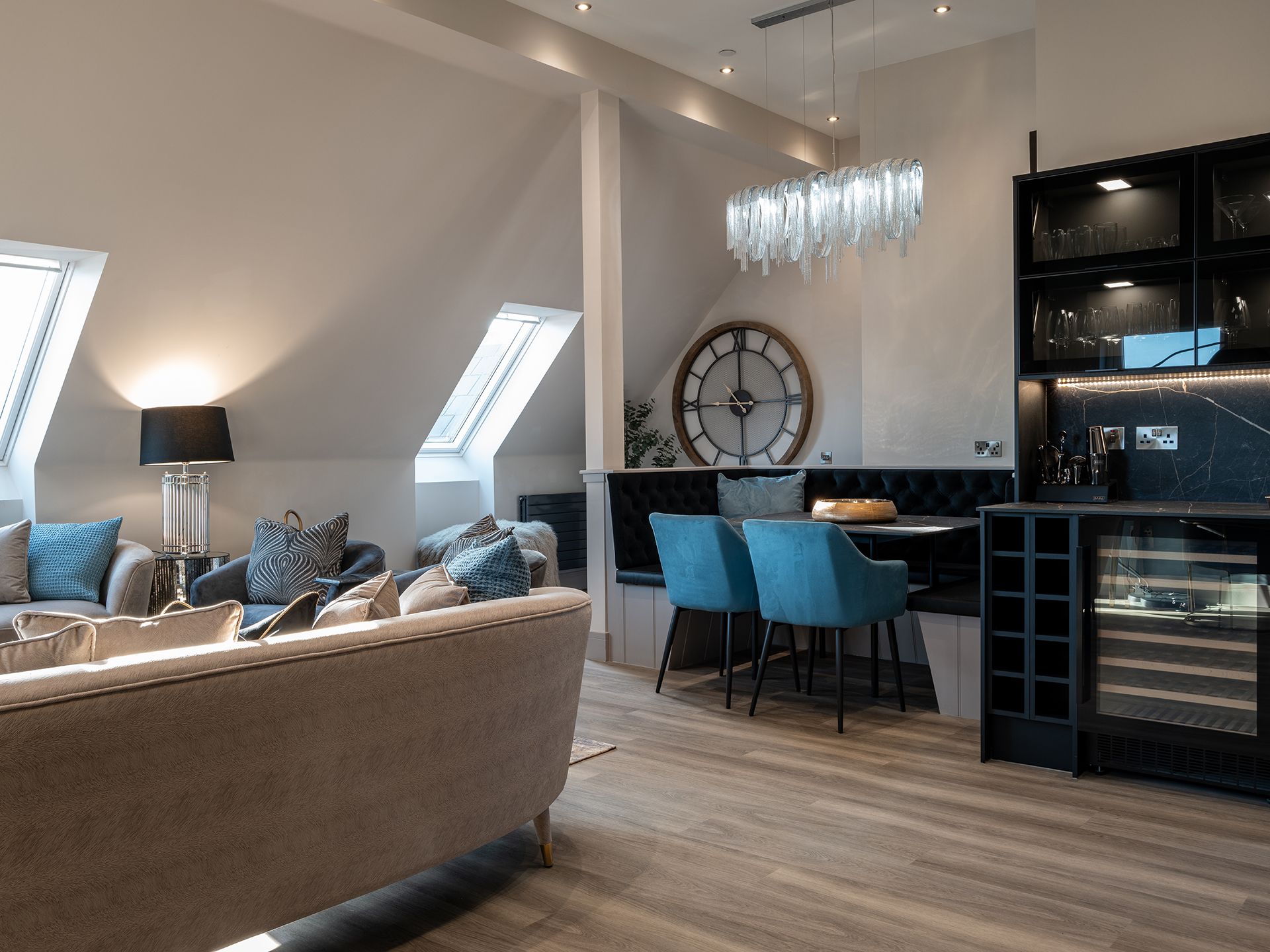 A living room with a couch , chairs and a clock on the wall.
