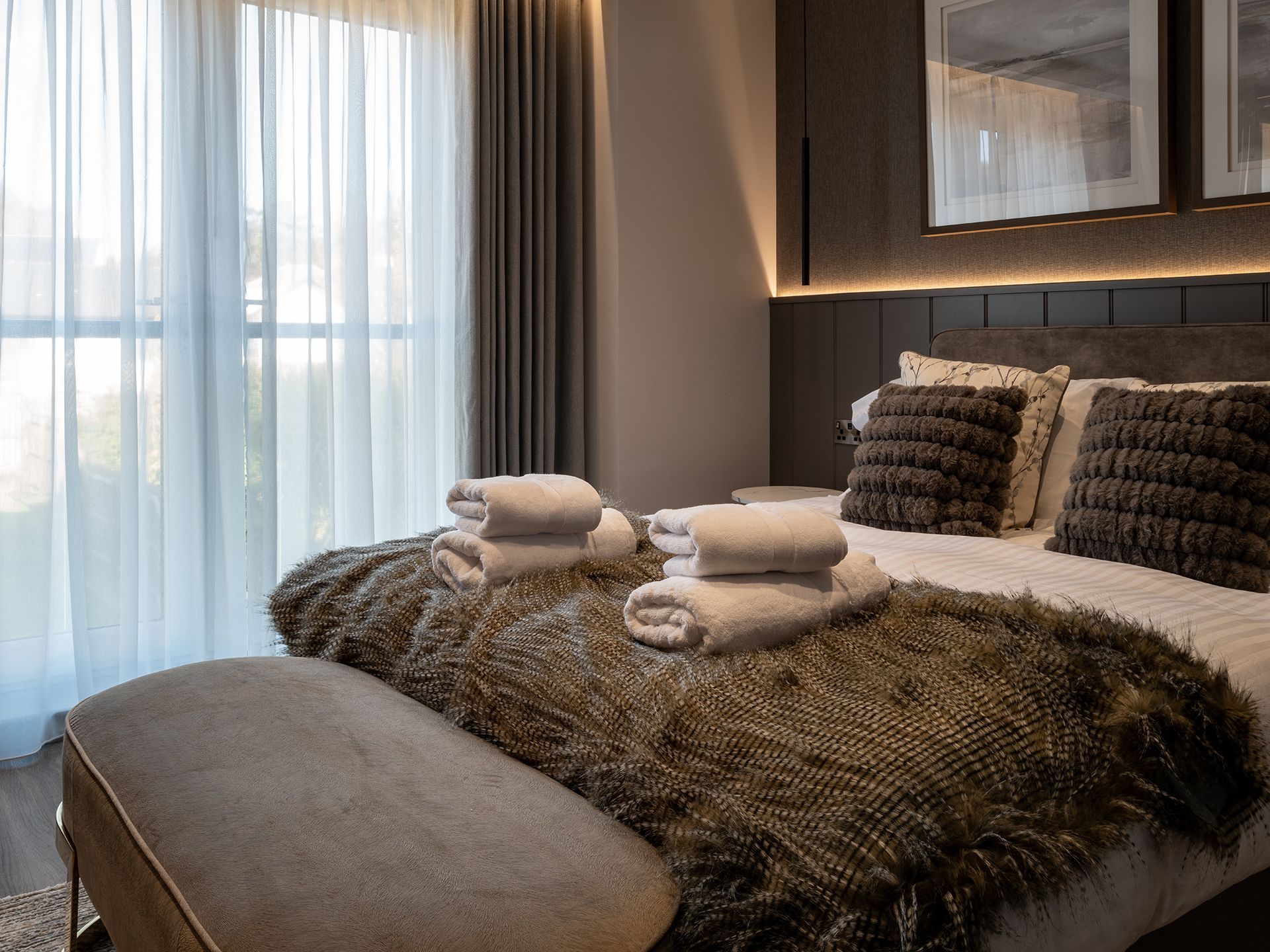 A bedroom with a bed , a bench , and a window.