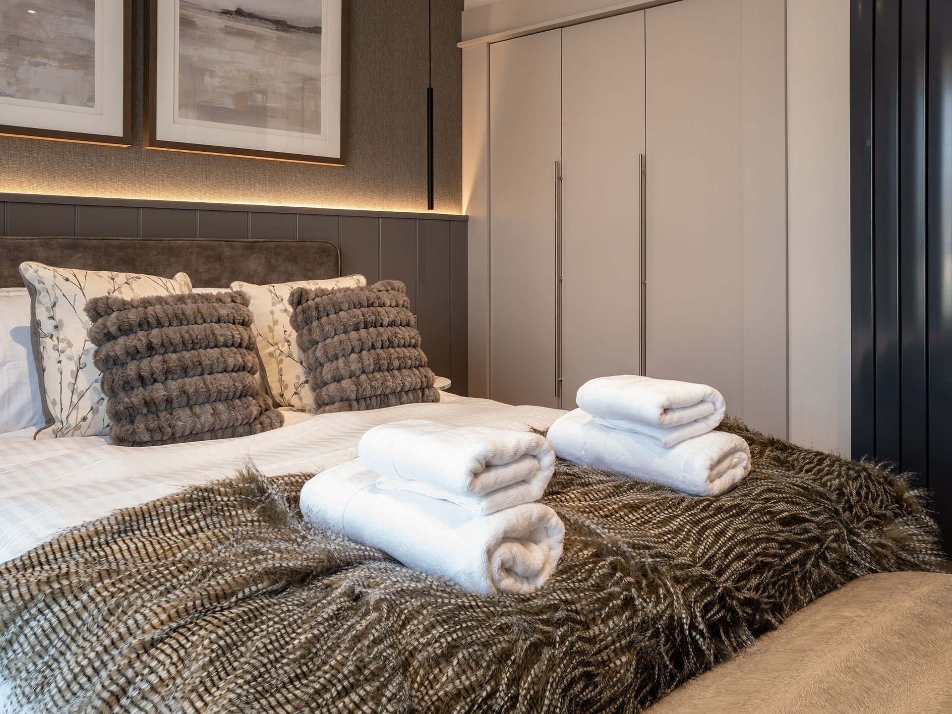 A bed with a blanket and towels on it in a bedroom.