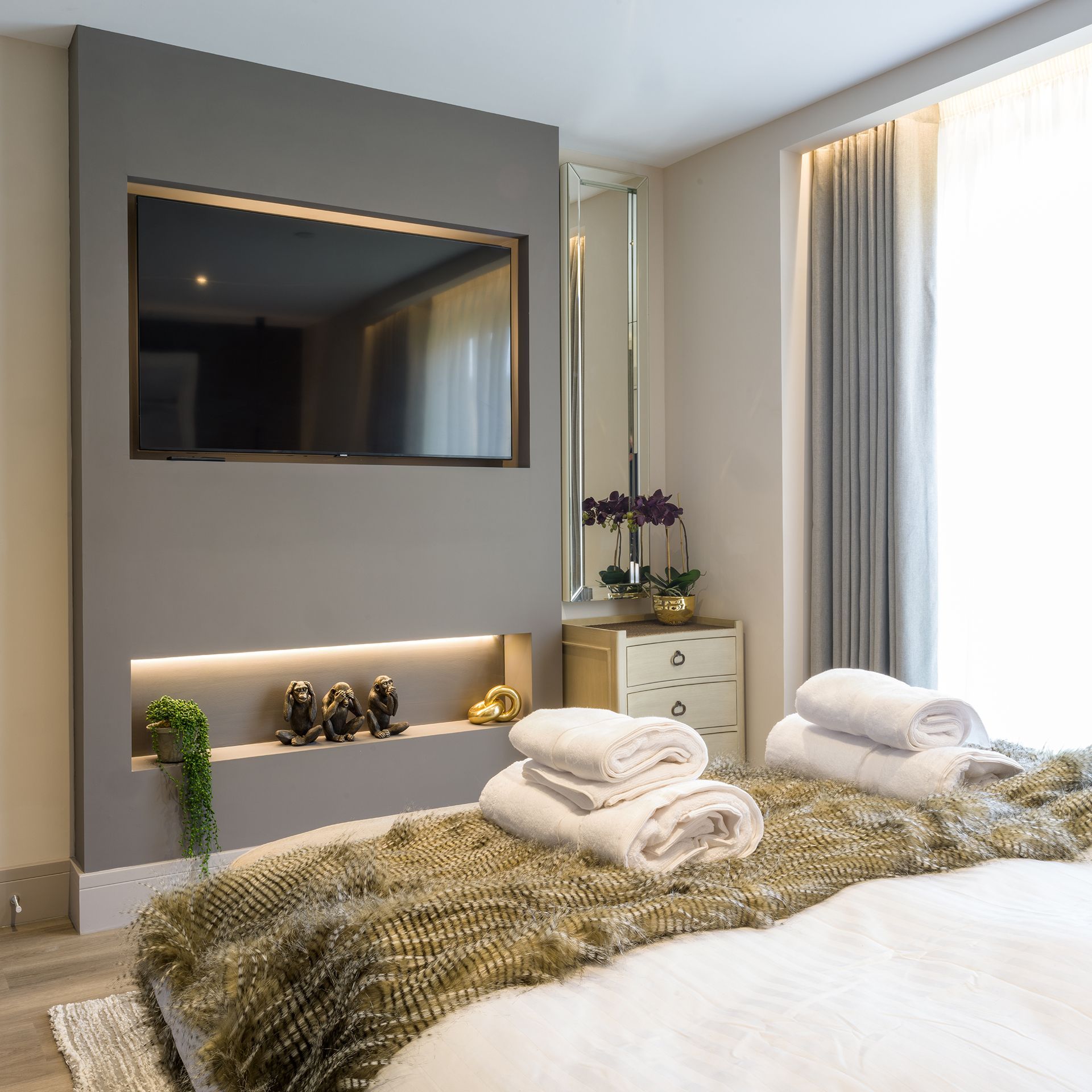 A bedroom with a large flat screen tv on the wall above the bed