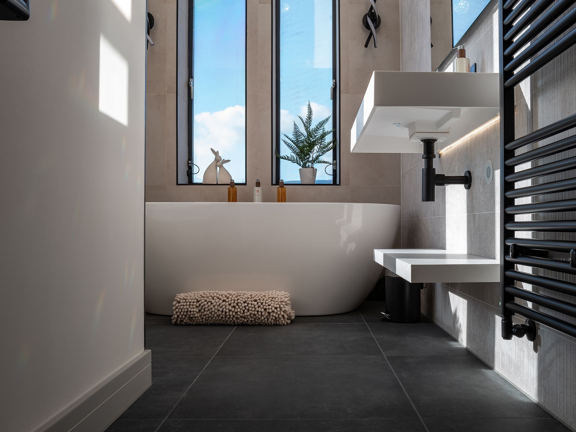 A bathroom with a tub , sink , and window.