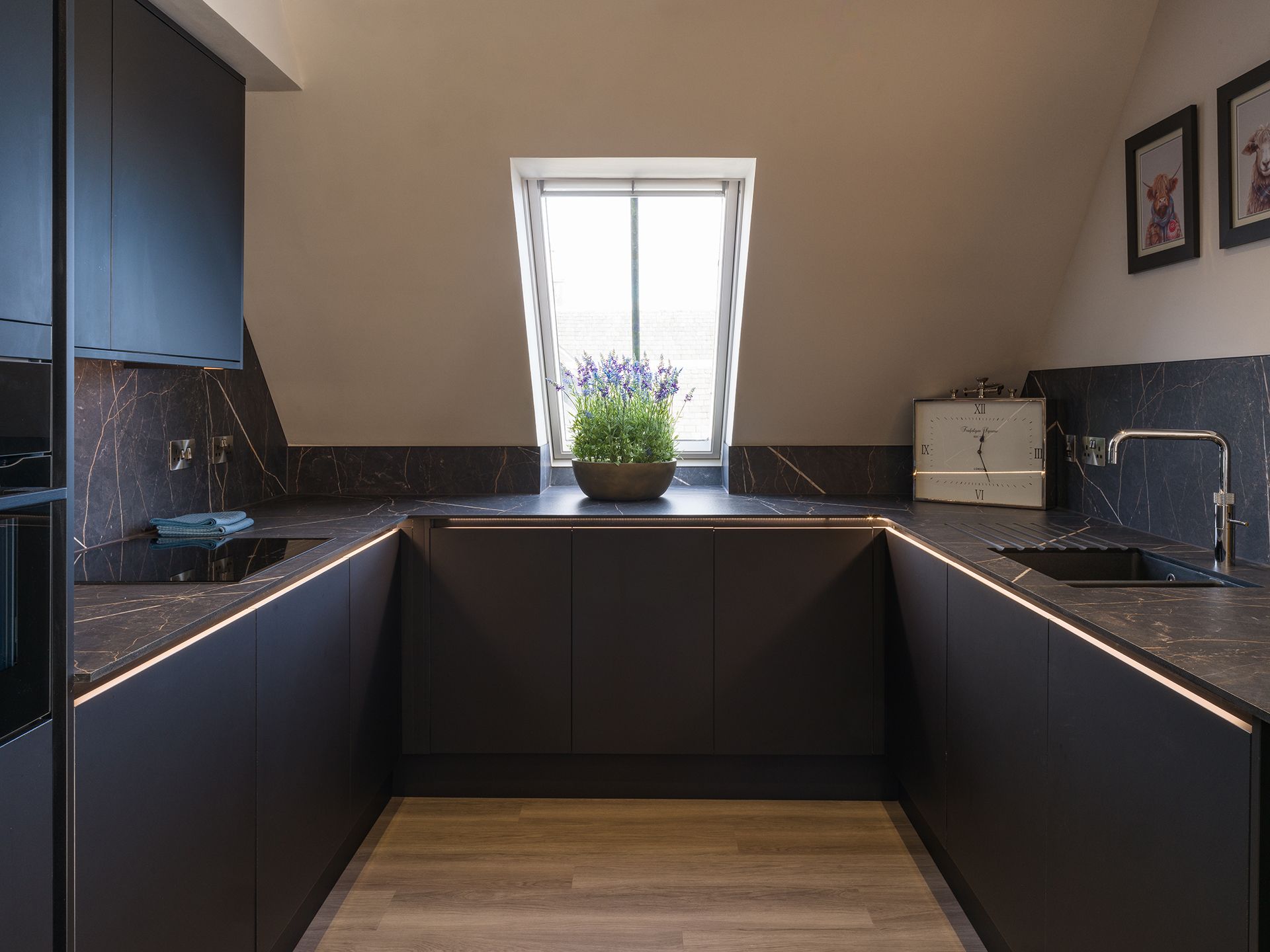 A kitchen with black cabinets , a sink , and a window.