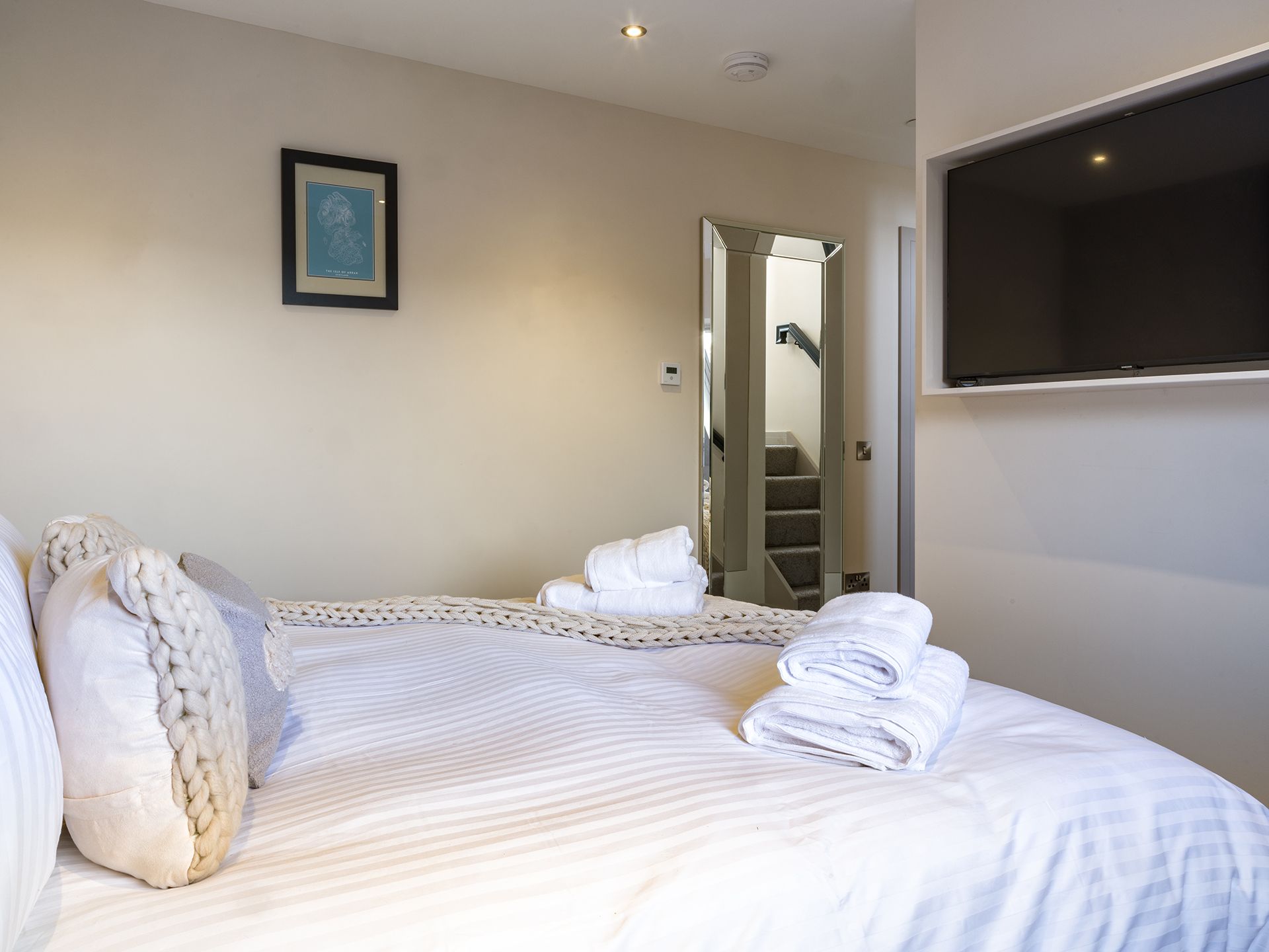 A bedroom with a bed , television and stairs.