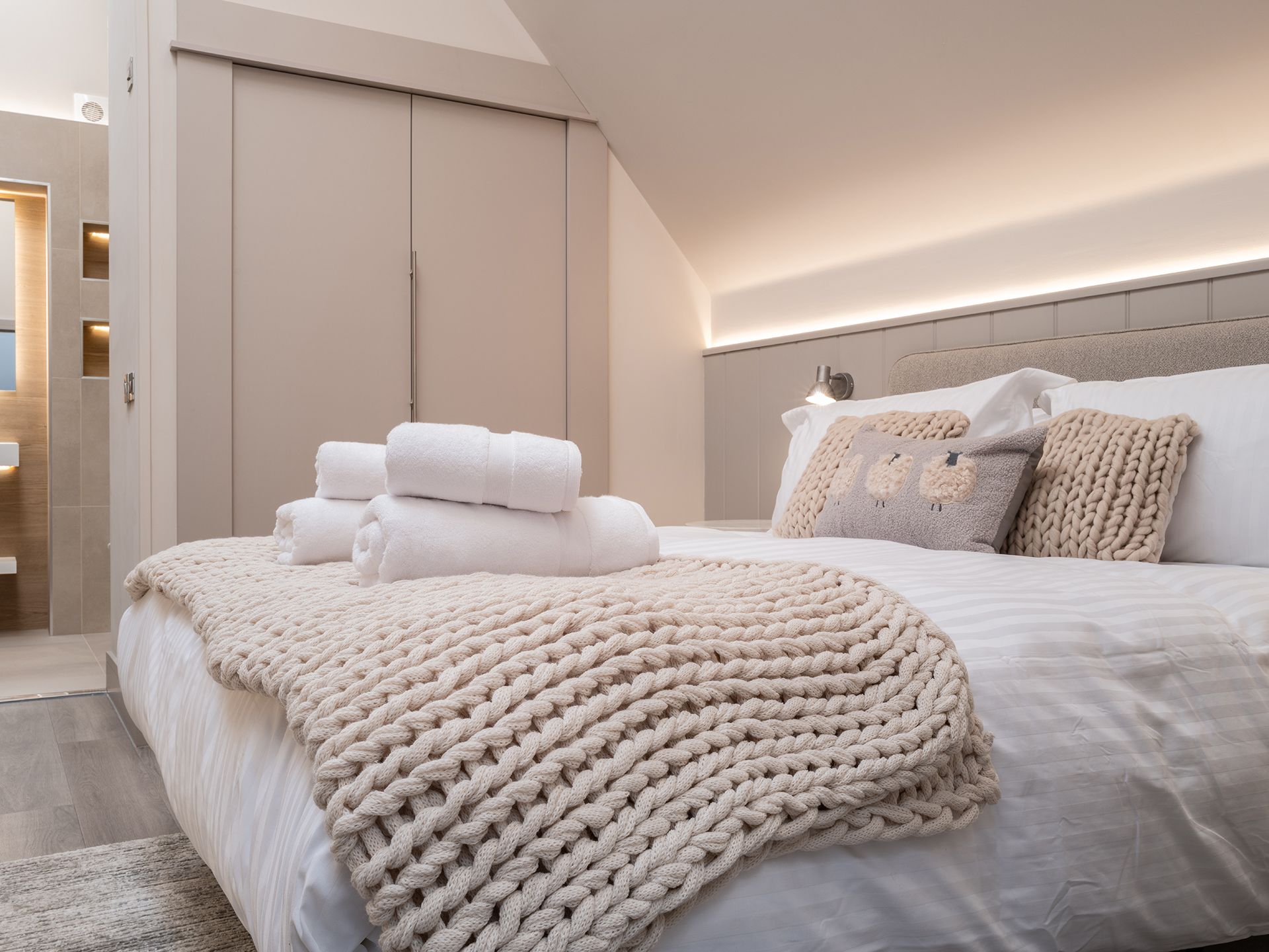 A bedroom with a king size bed and a knitted blanket on it.