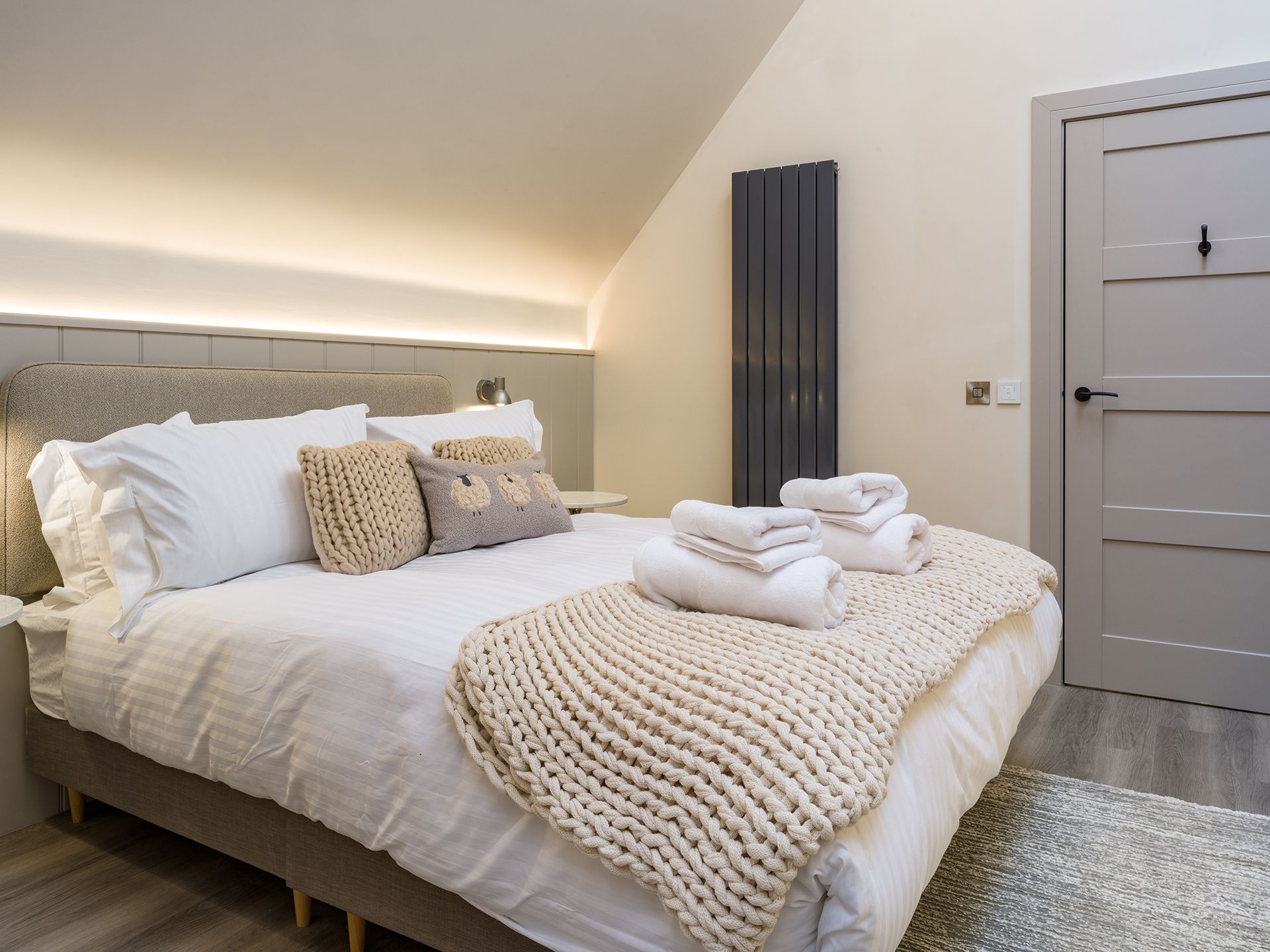 A bedroom with a king size bed and a knitted blanket on the bed.