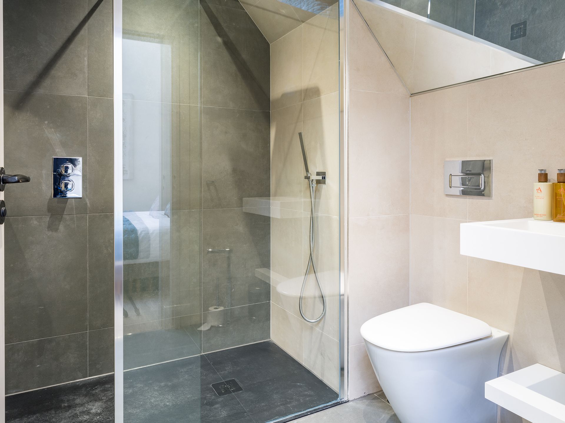 A bathroom with a walk in shower , toilet , sink and mirror.