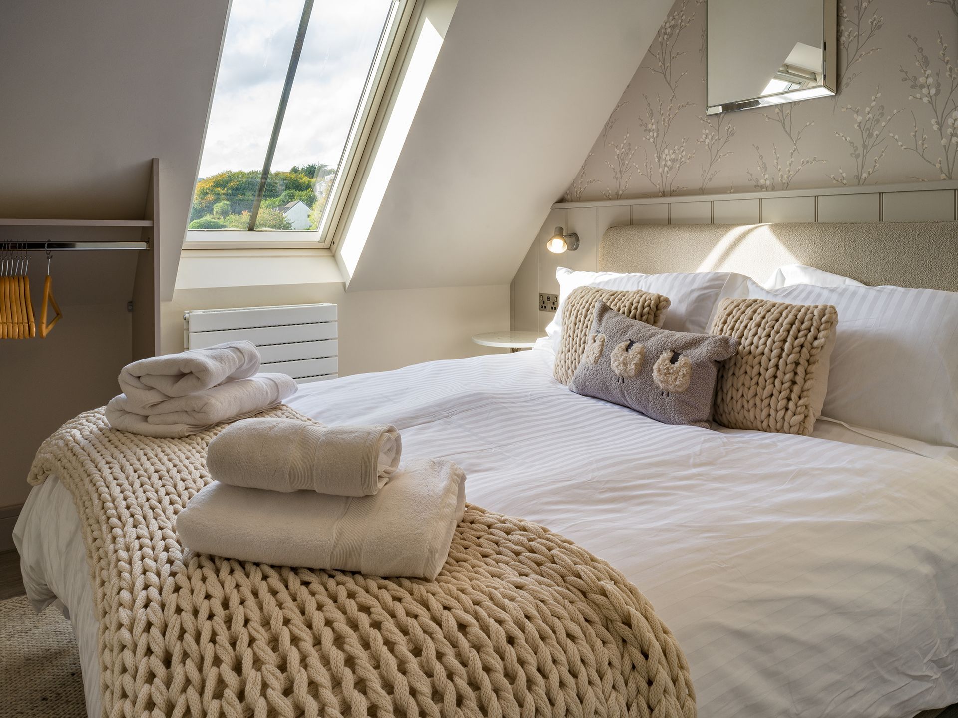 A bed with white sheets and pillows in a bedroom with a window.