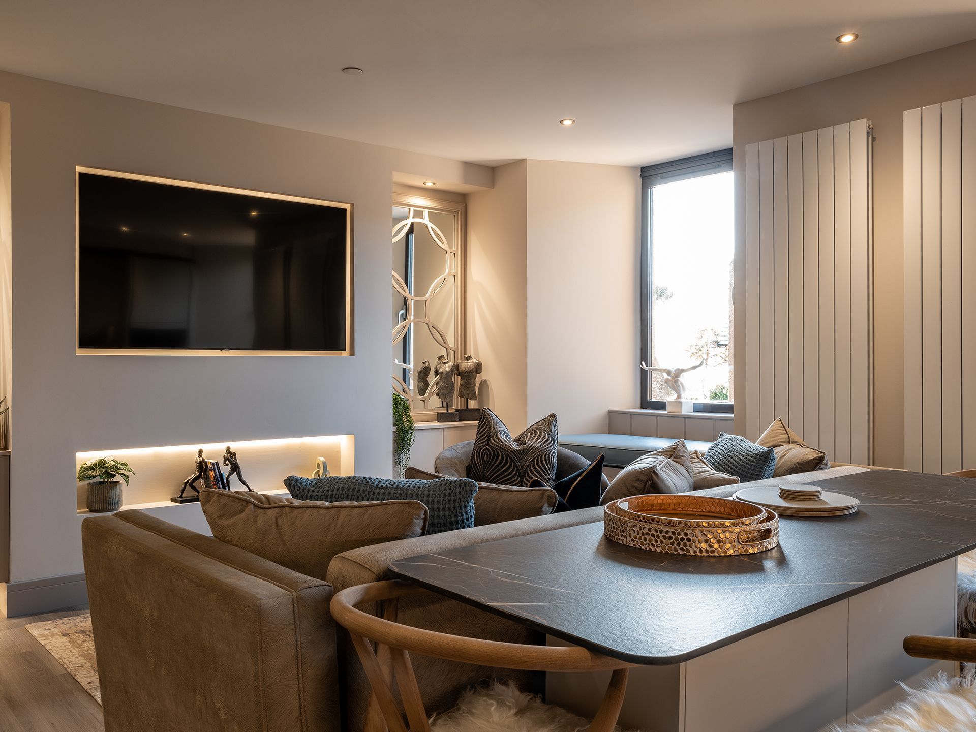 A living room with a couch , table , chairs and a flat screen tv.
