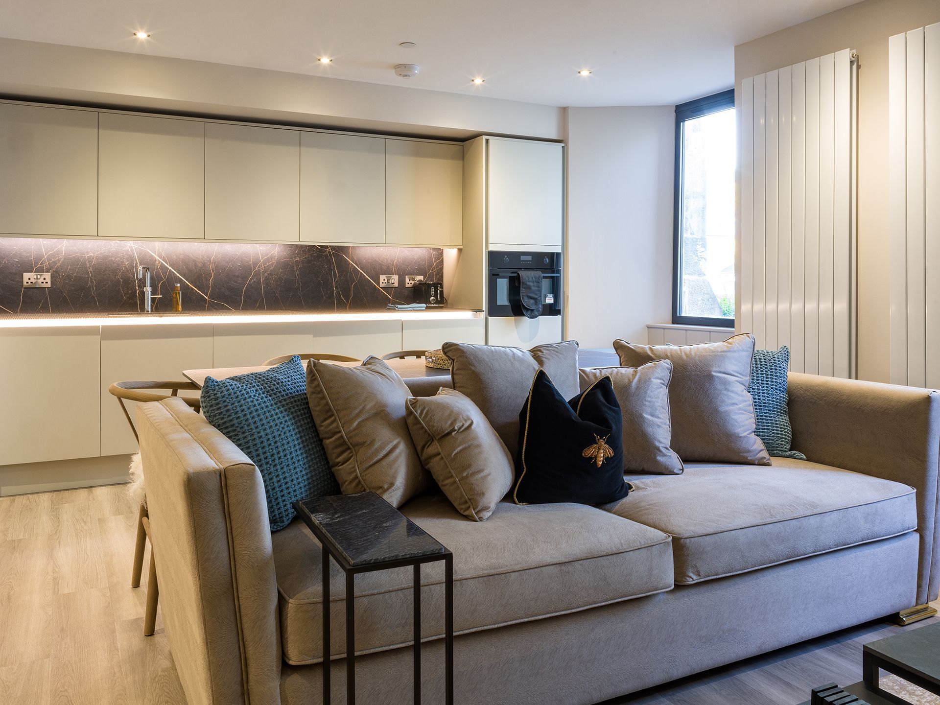 A living room with a large couch and a kitchen in the background.