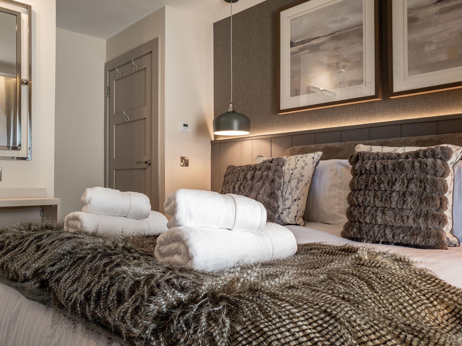 A bedroom with a bed , pillows , towels and a mirror.