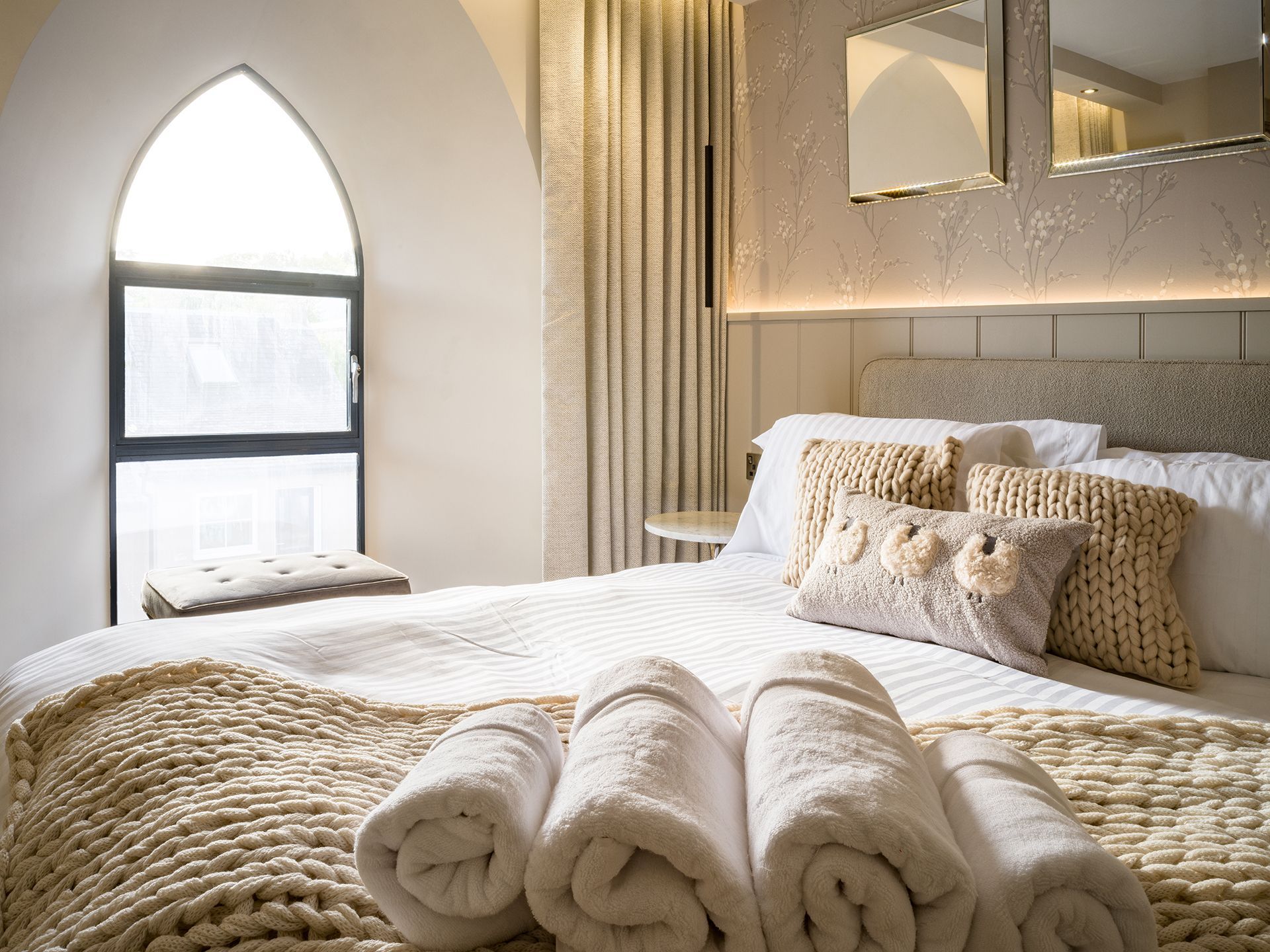 A bedroom with a bed , towels , pillows and a window.