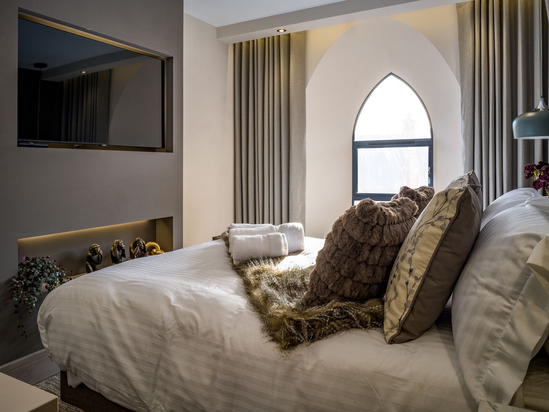 A bedroom with a bed , television , and window.