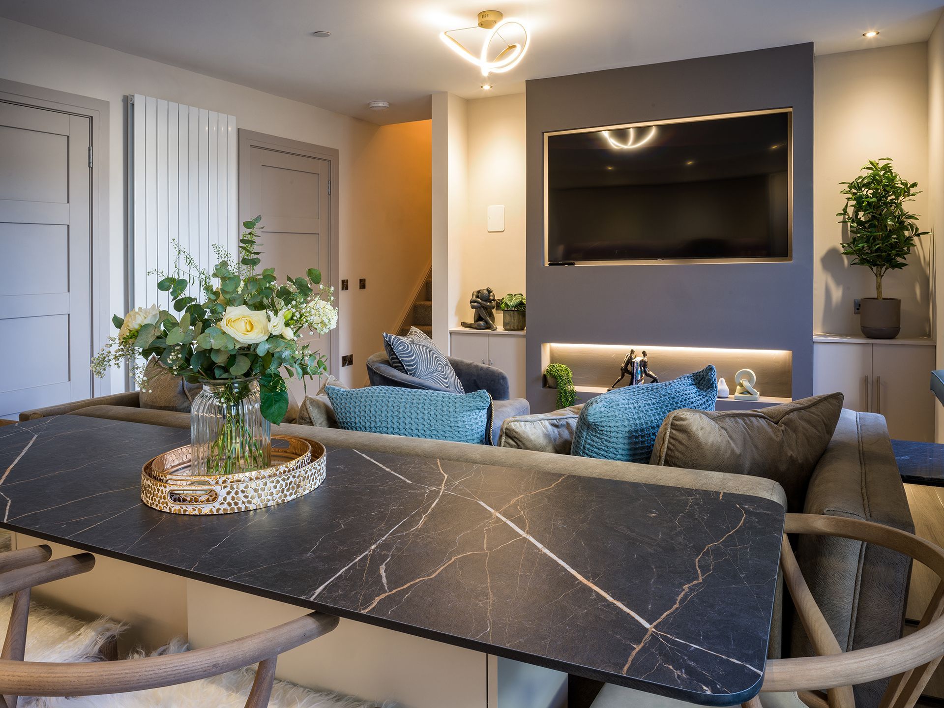 A living room with a couch , table , chairs and a flat screen tv.