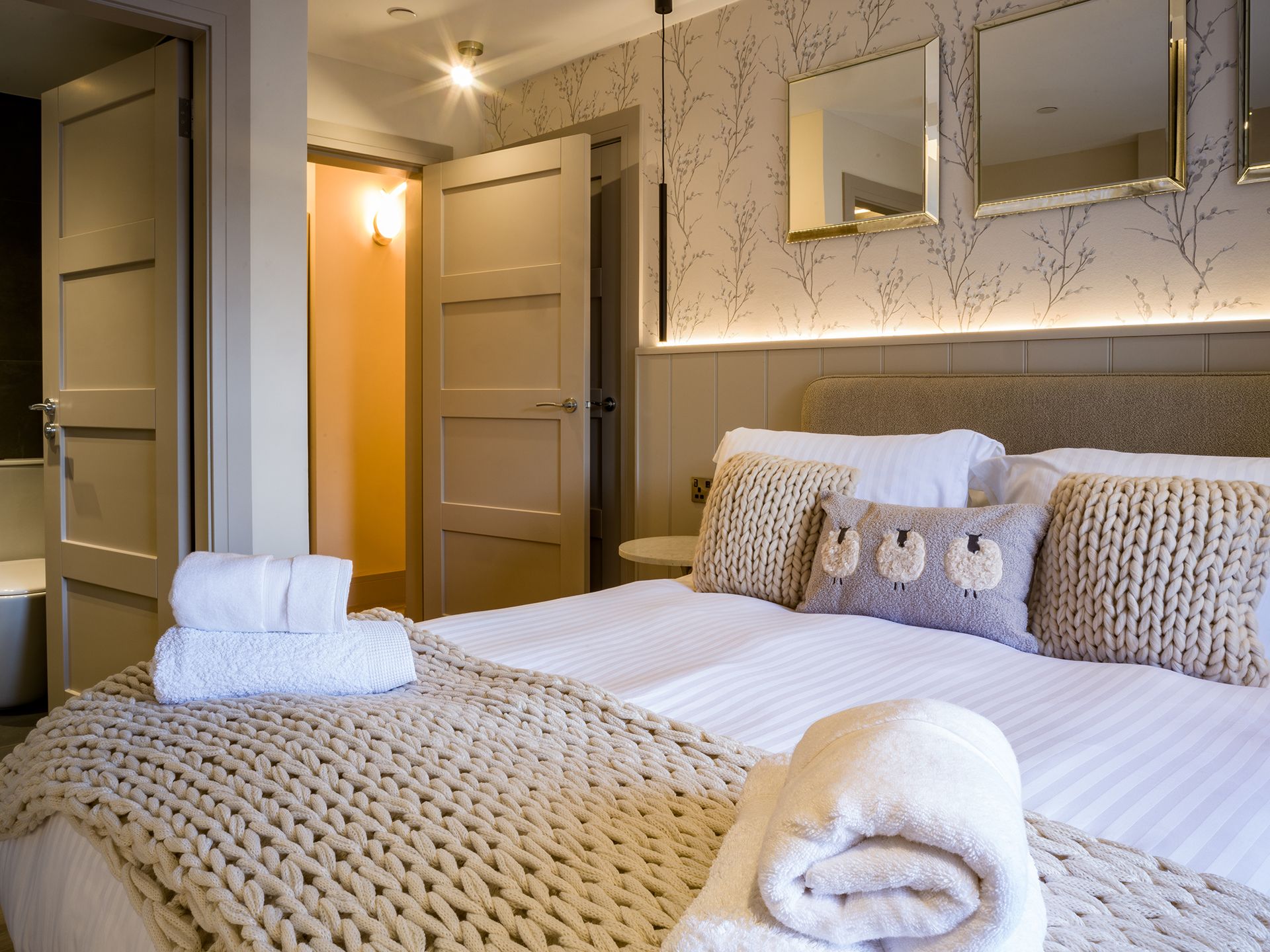 A bedroom with a large bed and a mirror on the wall