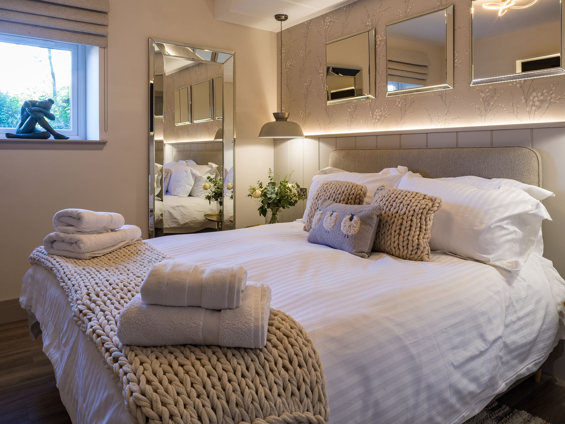 A bedroom with a bed , mirrors and a window.