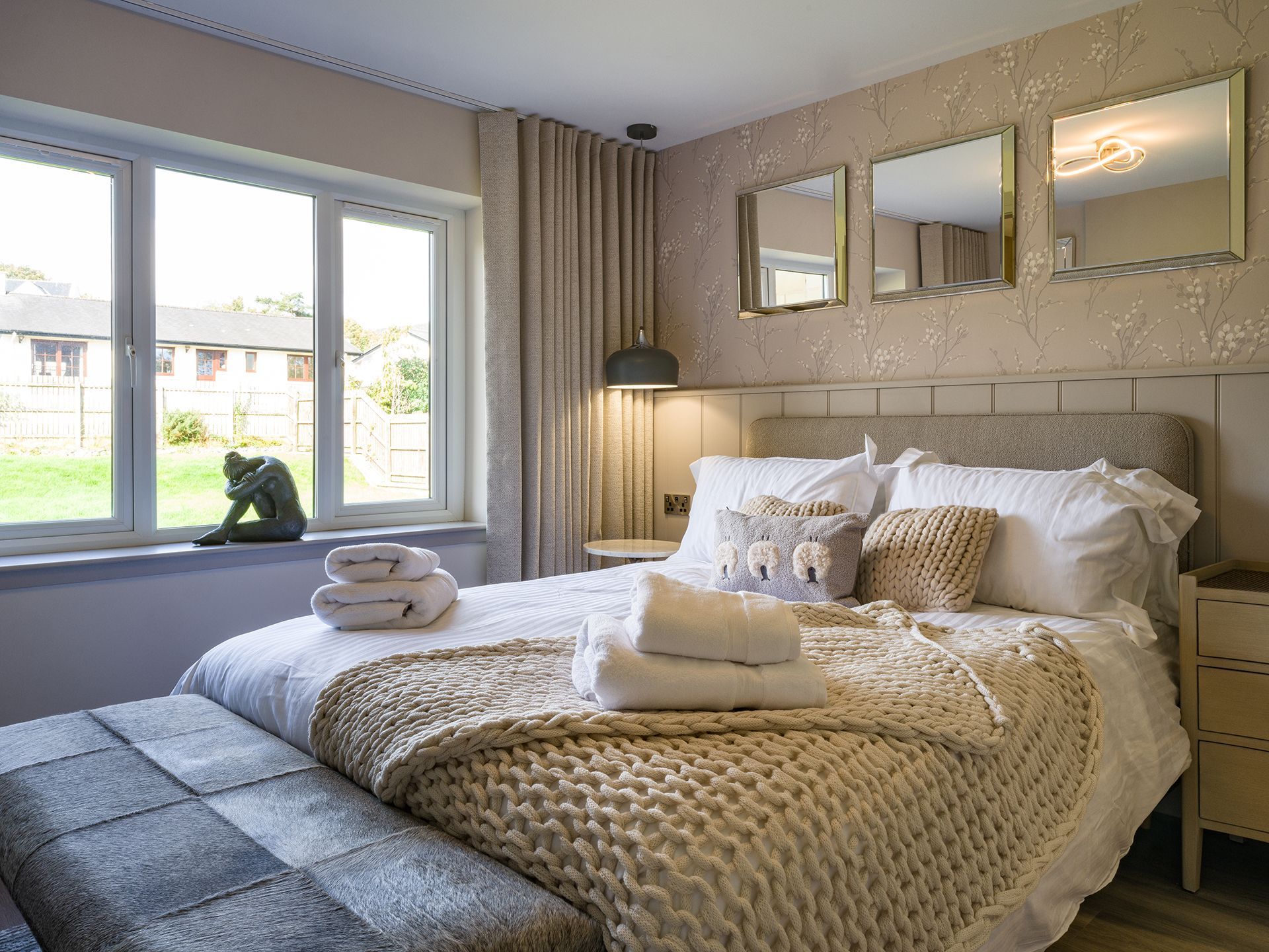 A bedroom with a bed , mirrors and a window.