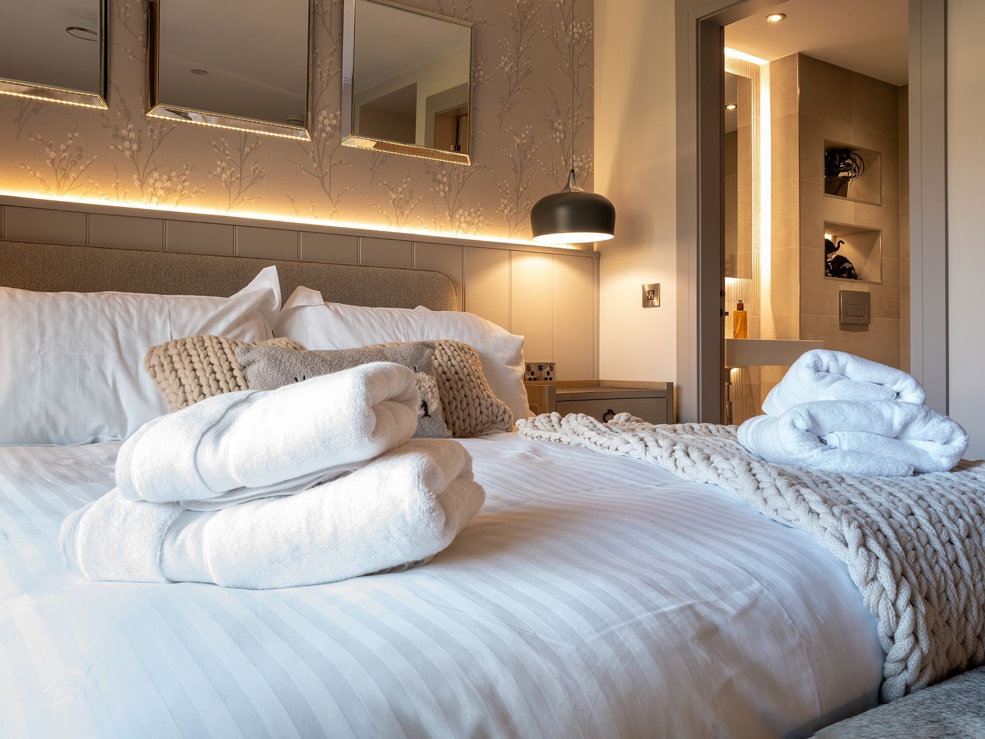 A bed with white sheets and towels on it in a hotel room.
