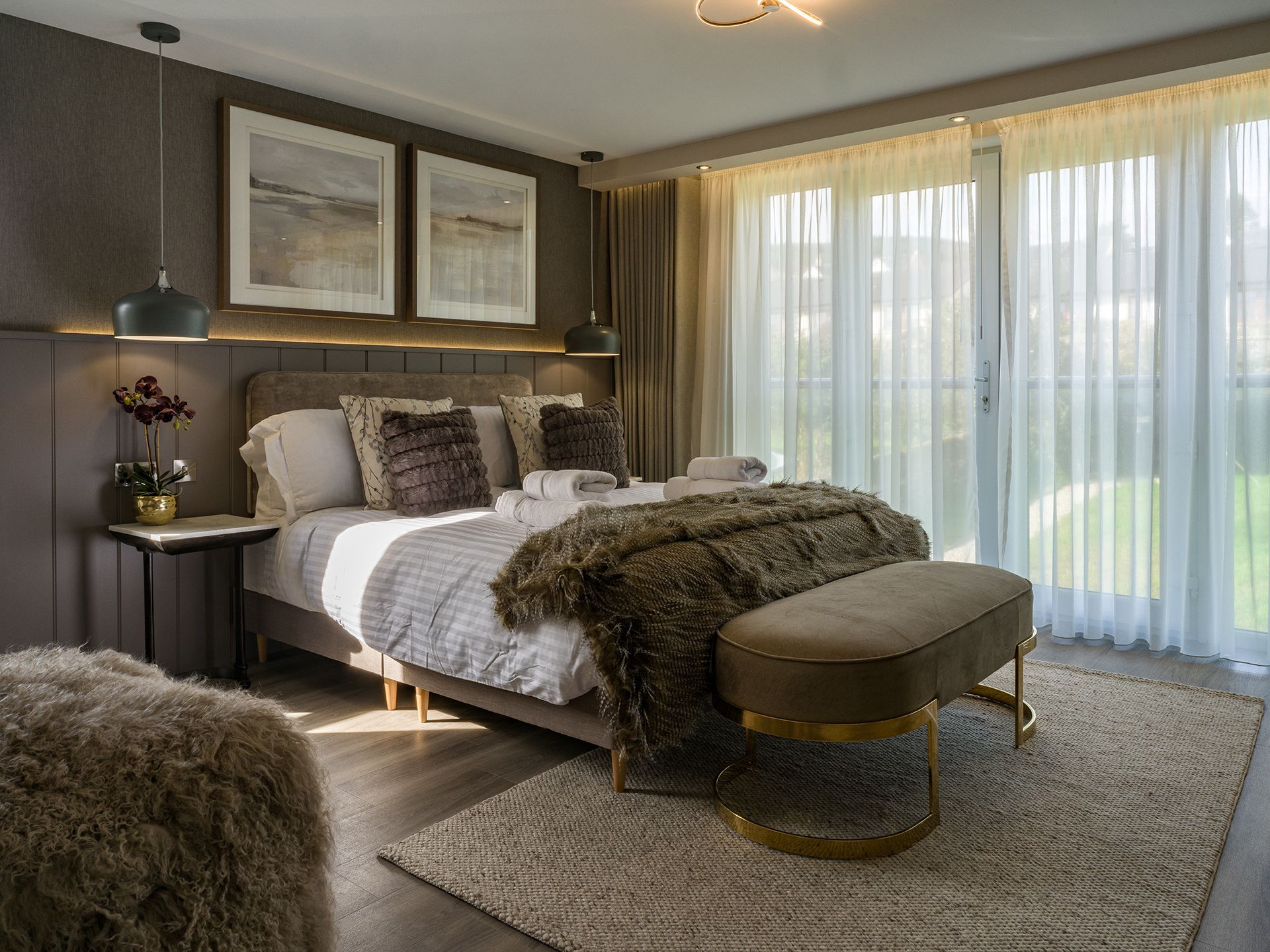 A bedroom with a bed , bench , rug and sliding glass doors.