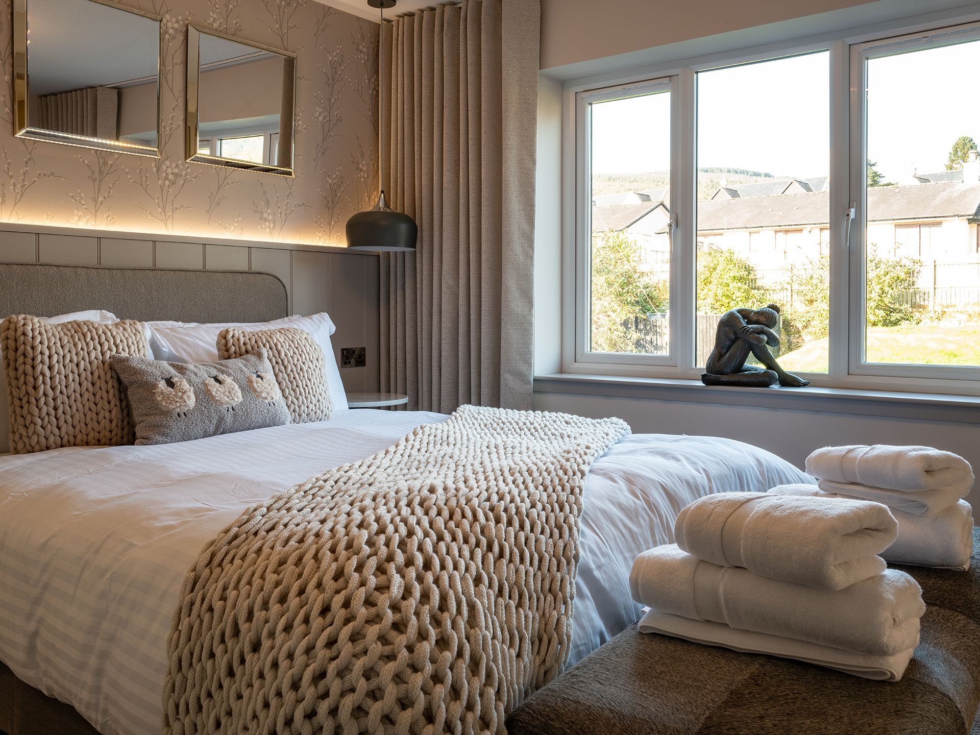 A bedroom with a bed , towels , mirrors and a window.