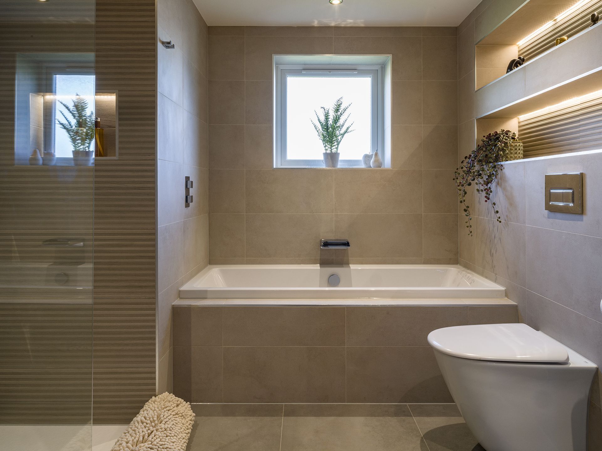 A bathroom with a tub , toilet , shower and window.