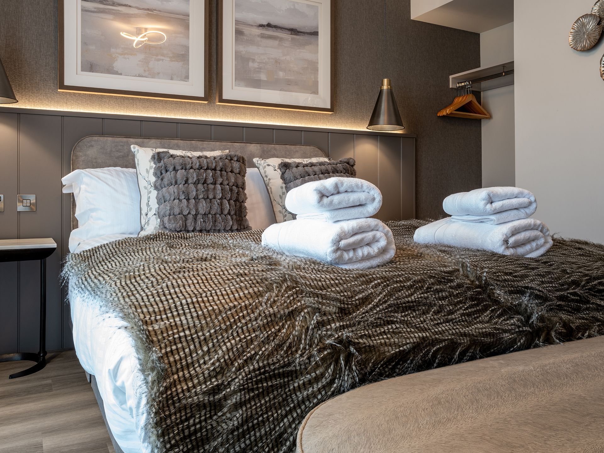 A bed with a fur blanket and towels on it in a hotel room.