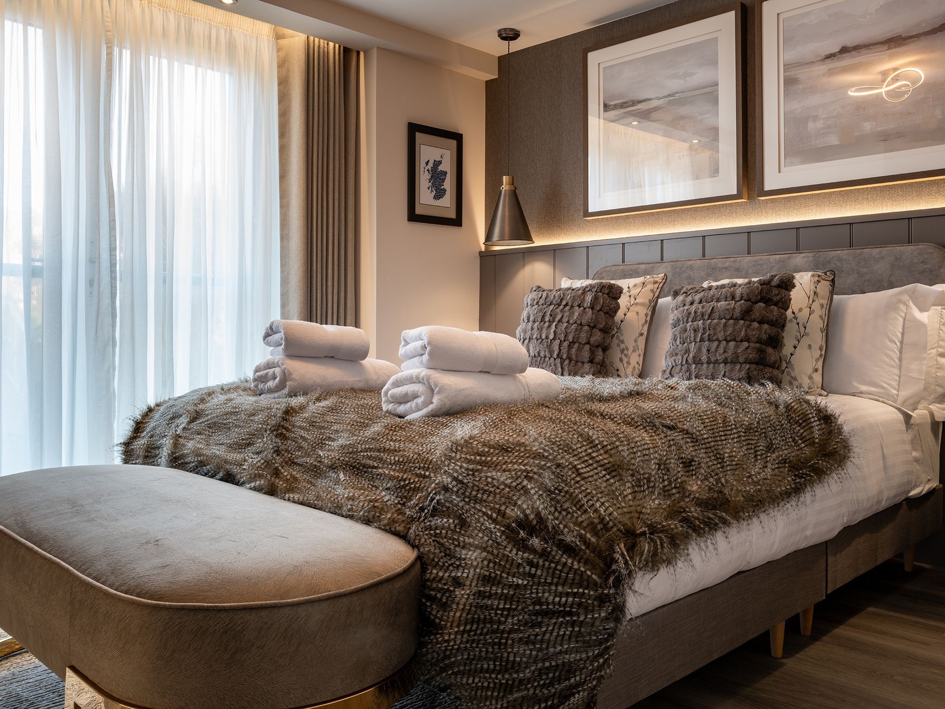 A hotel room with a large bed and a bench.