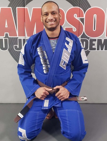 A man in a blue karate uniform is kneeling down