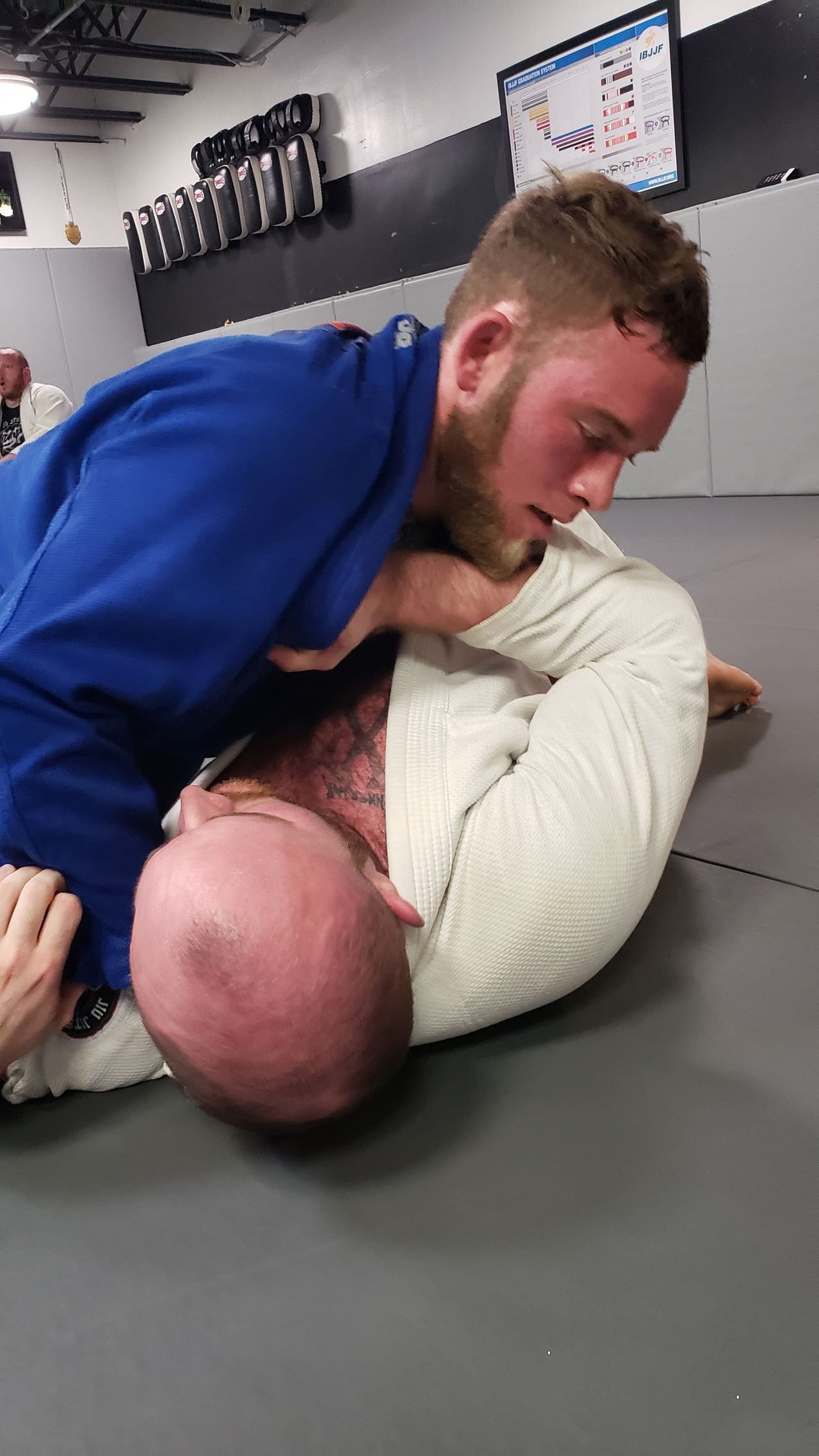 Two men are wrestling on a mat in a gym.