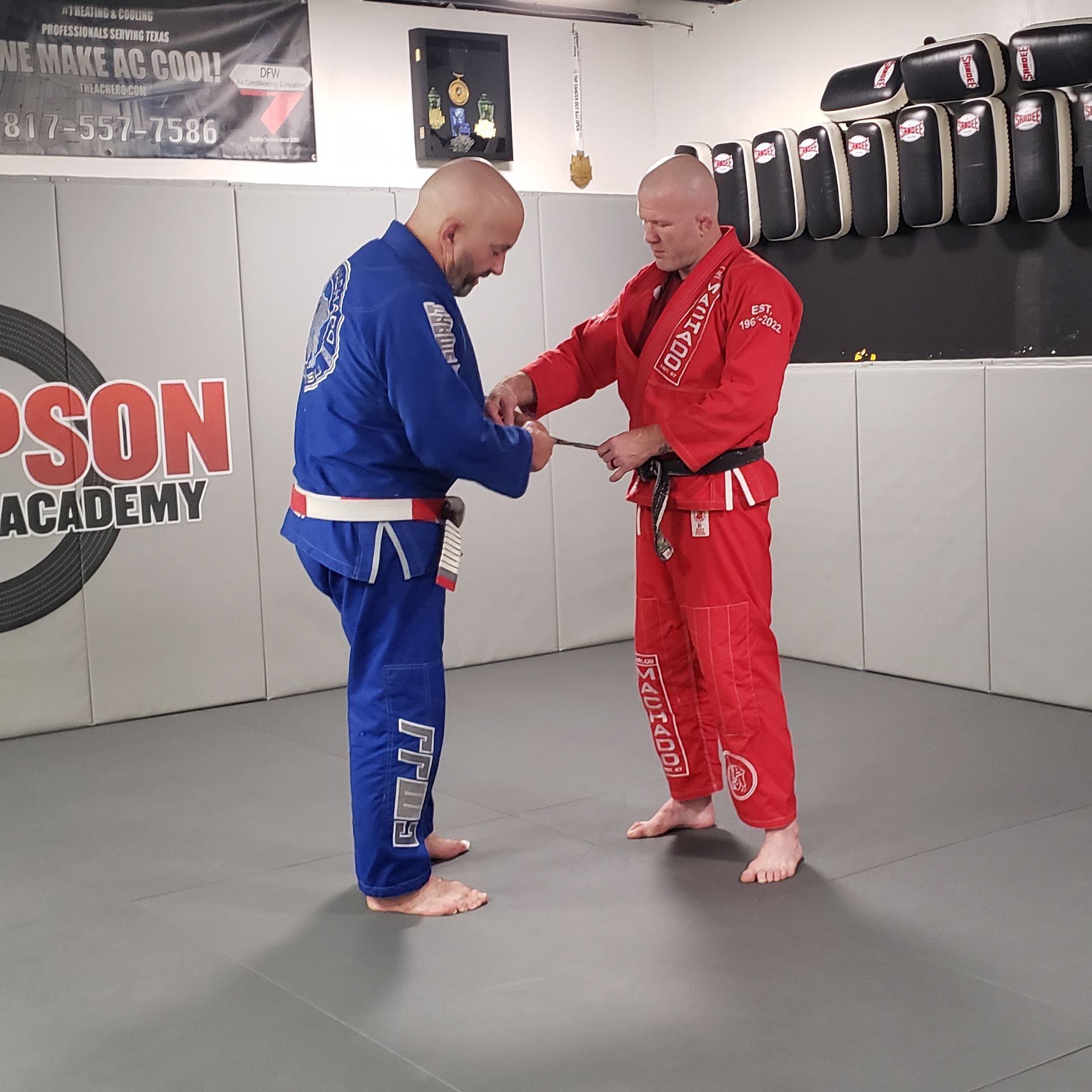Two men are standing in a room with a sign that says son academy