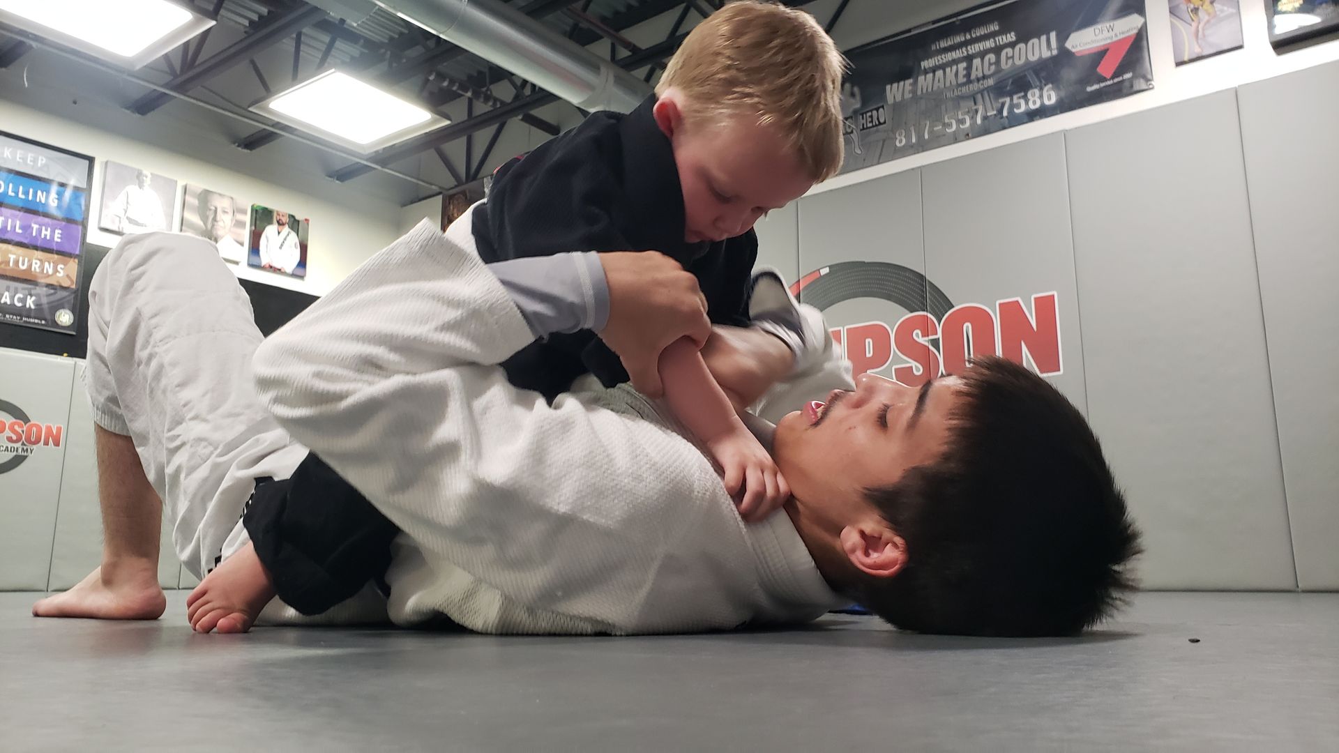 Two young boys are wrestling in a gym.