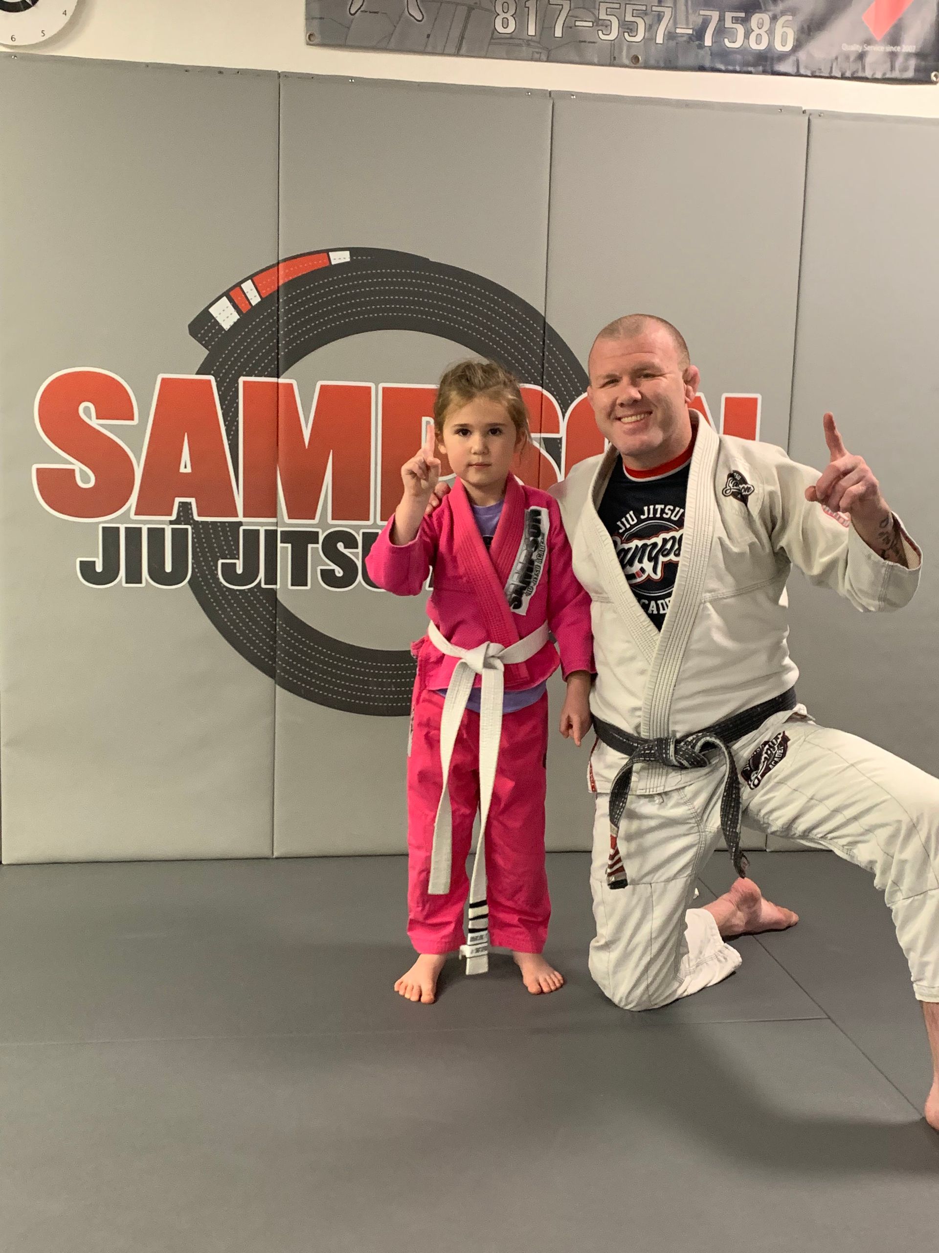 A man and a little girl are posing for a picture in a gym.