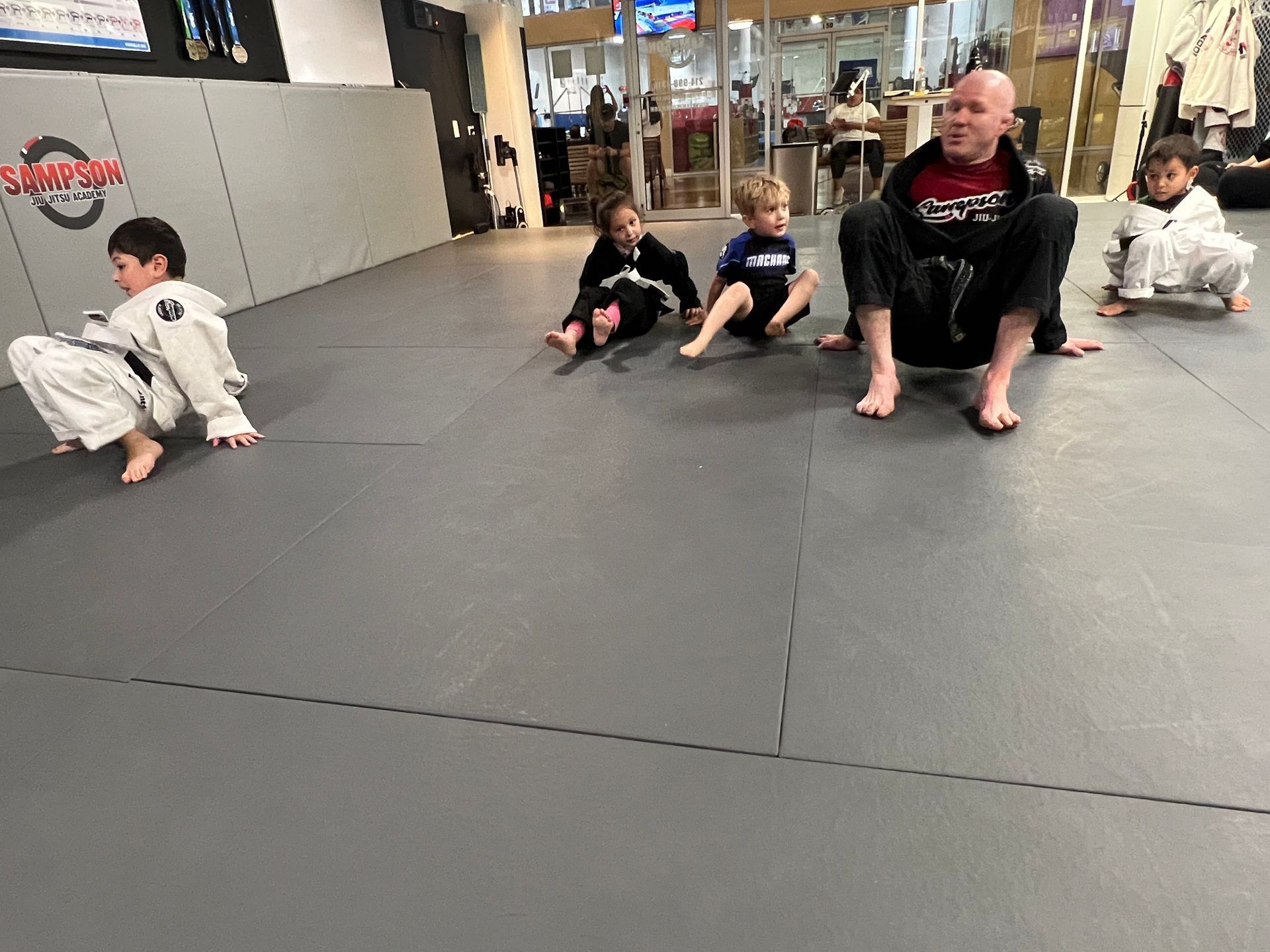 A group of people are sitting on a mat in a gym.